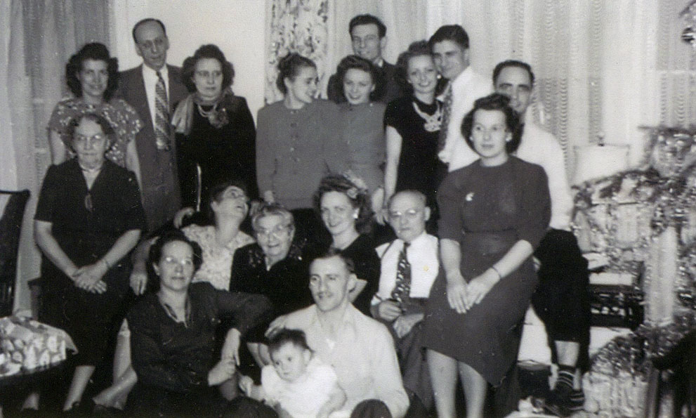 Ouellette family Christmas. There are many other babies behind the camera being wrangled by the older kids. 
Left top: Ida Mae (whose husband Oscar is taking the picture), Fran & Kate, Pat, Bernie & Jack, Toni & Joe. Left couch are: Mrs. Cowette (Fran's Mom). Right couch arm: Norm & Mary (my grandparents) On couch: Aunt Gin, Grandma Anna, Marie, Pa. On floor: Aunt Blanche, Frank (Marie's Husband) and the baby is either Frank & Marie's son Fred or my aunt Norma. They were the same age...

We've very lucky that five of these people are still living Marie, Norm, Mary, Bernie and Pat. View full size.