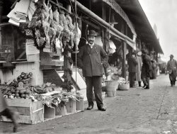 Washington, D.C., circa 1915. "P.K. Chaconas Co. Market." Pictured: Proprietor George Chaconas, whose grocery ("fancy fruits and vegetables") was at 924 Louisiana Avenue N.W. Harris &amp; Ewing glass negative. View full size.
Genuinely PleasantHow rare it is to see a sincere and guileless smile on a person's face.  Such direct and genuous happiness is impossible to fake.  This is a kind and happy man.
Oldest Greek MarketWashington Post Jul 2, 1922 


P.K. Chaconas &amp; Co., Inc.

The oldest established Greek-American firm in the Capital and probably the most prominent and successful one is the P.K. Chaconas &amp; Company (Inc.), at Ninth and Louisiana avenue northwest.
Its officers, P.K. Chaconas, president; P.C. Nicolopoulos, vice president; Chas. Chaconas, secretary and treasurer.  E.G. Nicolopoulos and P.G. Xedes, founded the business seventeen years ago, dealing in fruits, vegetables and groceries.  As the commission district grew, so did the company.  Their slogan reads: "Honesty in all business dealings," and it is safe to say that is quite correct.
The charter member of the firm, P.K. Chaconas, first started the business at 1440 P street northwest, near Riggs market, more than a quarter of a century back.  The latter is accredited for having originated in Washington the store on wheels, more familiarly known as the huckster wagon.
The aforementioned members of Chaconas &amp; Company are active in all Greek-American affairs in business and society.
Additional Notes:

Moved to pictured location ("Pickford's Old Stand") circa November 1906.
 The location of Louisiana Ave has changed over time such that Ninth and Louisiana do not intersect on the contemporary map of Washington D.C.  The location of this photo would be in what is now eastern edge of Federal Triangle - just west of the current National Archives building.
 Top portion of Washington Monument visible in backgroud.
The Washington Post refers to "huckster wagons" as early as 1878
 Earliest mention of 'Chaconas' in Washington Post archives is Aug 14, 1894: George Chaconas was fined (along with a dozen other Greeks and Italians) for lingering too long and obstructing the street with a vending push cart.
 This block of Louisiana Avenue is just west of Center Market and seems to have accommodated an overflow of merchants and wholesalers.


1909 map from Baist's Estate Atlas
His wife, and fluffy bunnies, tooIs that his wife we see in the left-hand side of the frame?  Also note the fresh rabbits, atop the open crates.
PrideI see a man who is so very proud of what he has built up (I would bet from nothing) since he, or maybe his parents came to the United States.  The Land of Opportunity.
Yech.One would think he would stop smiling long enough to sweep that filthy sidewalk he is selling food on !!
The Source of GreatnessI fully concur with Lincoln's remarks and would like to take it a step further. Small businesses (like this one) were/are the foundation for a community's and a country's greatness. His genuine happiness was surely the result of more than commercial success. We can learn a great deal by understanding the personal stories of such gentlemen and ladies.
Local LandmarksNote the Washington Monument sticking up behind the roof.
Xmas 1915I love the Christmas greenery. (The notice by the window is promoting a Charity Ball for Monday, January 3, 1916.) When I was a small child in the mid-1950's, my grandma used to go to a butcher where you could pick out your live chicken and they would kill, clean and dress it for you. This brings back memories. He does look like a happy man, as does she.
What made America great!This is a beautiful picture of a man truly proud of what he does and where he does it.  
Trusting soulTwo cash registers, no waiting!  I bet they wouldn't last two minutes out in the open street today.
Haconas?The banner at the top center, under the overhang: we can see a partial K and a period, followed by HACONAS &amp; CO. Where's the C?
[The left section overlaps the right. - Dave]
Central MarketIs this essentially part of the old Central Market?
Deja viewIsn't this the same butcher shop that was proudly displaying a row of greasy old possums a couple of weeks ago?
[That was in New York. This is Washington. - Dave]
My great grandfatherThis is a photo of my great grandfather in front of the business that he built up from nothing. Although our times did not cross, I grew up with the family stories, seeing this picture is like getting a piece of my history. Where did you find this and do you have any others?
[This photo is part of the Harris &amp; Ewing collection of glass negatives at the Library of Congress. There's a photo of a Chaconas delivery truck here. - Dave]
(The Gallery, D.C., Harris + Ewing, Stores & Markets)