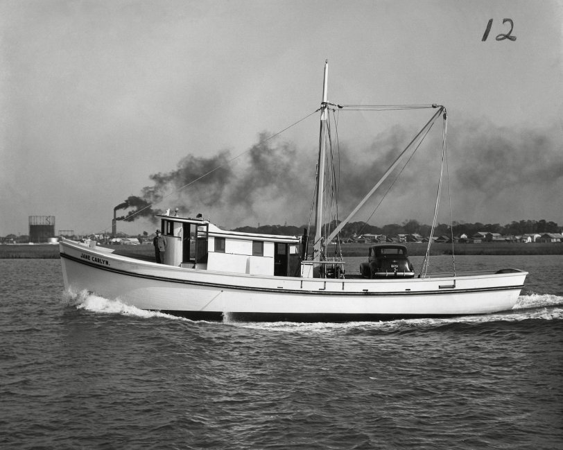 The 'Jane Carlyn' is shown here freshly launched and leaving the Diesel Engine Sales Co. docks in St. Augustine, Florida. Roland Styron stands at the bow of his brand new 65' wooden shrimp boat. Capt. Styron had a fish house in Hobucken, N.C. beside the R.O. Mayo fish house and later operated a fleet of shrimp boats that travelled as far south as the Florida Keys. Diesel Engine Sales Co. (DESCO) was a the leading builder of shrimp boats in the US and built 2272 wooden fishing vessels between 1943 and 1982. Photo taken in 1944. View full size.
