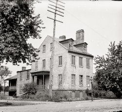 Washington, D.C., circa 1901. "Carberry [Carbery] Mansion." Built for Thomas Carbery in 1818 at 17th and C Streets N.W. National Photo Co. View full size.
Fixer-UpperThis is what used to be called a handyman's special, needs a little work.  I'm not a snob, but calling this a mansion is a bit of a stretch.
Double-dare SpookyNothing in a neighborhood could fire a young boy's imagination quite like a huge run down and empty old house.  I wish that I, along with my boyhood friends, could jump into this picture today.
On the EdgeThe mansion was razed in 1903; Carbery was Mayor of Washington from 1822 to 1824 and I'm sure the mansion was in better shape back then!
&quot;Miracle House&quot;I suppose I don't have the eye for spookiness which other commenters readily pick up on: before finding the following article I viewed this house as a typical run-down dwelling.  Also, it seems to me (a non-Catholic) that Prince Hohenlohe received an inordinate degree of credit for Ms. Mattingly's "cure."


Miracle House
by Marie Lomas
Washington's Miracle House has again come to light.  A water color painting discovered a few days ago by the curator at a local museum brings up a story stranger by far than many of the bizarre tales of fiction. Although separated from its identification marks, the picture has been established as a rear view of the Miracle House, or Ghost House, as it was sometimes called, down in the neighborhood of "Foggy Bottom."
...
Even as the residence of Capt. Thomas Carbery in 1824, it was familiarly known as the the Miracle House, for it was here that the famous Mattingly miracle occurred. 
The legend, which will accompany the picture now carefully guarded behind locked doors of a display case in the D.A.R. museum, states: "This house, in 1824, was the residence of the Mayor, Capt. Thomas Carbery, and living with him was his widowed sister, Mrs. Ann Mattingly, a great sufferer and confirmed invalid. Marvelous cures were being made by Prince Alexander Hohenlohe, a Catholic Priest of Bomberg, Germany, throughout Europe.  His Highness stated to the Diocese of Baltimore that he would offer up a prayer the tenth of every month at 9 a.m. for those living out of Europe.
"Mrs. Mattingly performed a novena, or nine days' devotion, commencing March 1, 1824, assisted by the pastor of St. Patrick's Church, and on March 10 she was relieved of all pain and, although bedridden, rose from her bed and opened the door to callers."
This miracle was sworn to before John Marshall, Chief Justice of the United States, and immediately aroused great excitement throughout Washington.
No doubt the setting was partially responsible for many of the later stories in connection with Miracle House, which soon became and enigma to the residents of lower Washington.  Situated near the canal and lock houses, which still stand on Constitution avenue and Seventeenth street, it was at the edge of what was considered a dense and dangerous jungle.  The nearby shores were covered with an almost impenetrable growth of somber trees shrouded in tangled vines.  Hoarse croaking of frogs and the screams of swamp fowl pierced the abysmal darkness of the nights.
Even Scott, the major-domo of the great marble edifice built by the D.A.R. on the site of the "Ghost House," vouches for the mystery of its unknown inhabitants.  He recalls today his frog-catching expeditions into the swamps near the house, "We could see people in there and sometimes a light," he said, "but nobody ever came out."
In its later days it was deserted, but the latest happenings at the "haunted house," as it was called by the little Negro boys of Foggy Bottom, continued to be the news of the day.
The house was demolished in 1903 to make way for Memorial Continental Hall.  Perhaps when shadows lengthen and the massive doors are locked for the night the spirit of the haunted house still lingers in the familiar surroundings of aristocratic Hepplewhites,  Chippendales, Duncan Phyfes and shining Steigle glass. After all, it was in the basement of this museum, on the site of the Miracle House that the picture came to light.

Washington Post, Nov 3, 1937 


LOTS of wires on that pole...So.. are the wires telephone/telegraph wires or "newfangled" electric wires?  In 1901 electricity was relatively new, while telephone/telegraph had been around for 25+ years by that time.
What is interesting is that there was no such thing as a big trunk cable.  Looks like everything was run individually.   I can remember seeing other old photos here on Shorpy of city scenes that showed poles literally ready to fall over with the weight of so many wires on them. 
Imagine what our cities, and towns for that matter, would look like today if poles were huge with tons of individual wires running on them!
(The Gallery, D.C., Natl Photo)