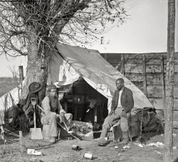 November 1863. Culpeper, Virginia (vicinity). "Contrabands [runaway slaves]." The man on the right is identified in this photo dated October 1863 in Bealeton, Va., as "John Henry, servant, at headquarters, 3d Army Corps, Army of the Potomac." Wet plate glass negative by Timothy H. O'Sullivan. Photographs from the main Eastern theater of war, General Meade in Virginia. View full size.