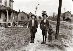 On streets near Daniel Mill. Lincolnton, North Carolina. November 1908. Right hand boy is Dan Biggerstaff. 10 years old. Has worked three years. Goes to school now (he says). Left hand, John Erwin. Said 11 years old. Has worked nights. Photograph by Lewis Wickes Hine. View full size.