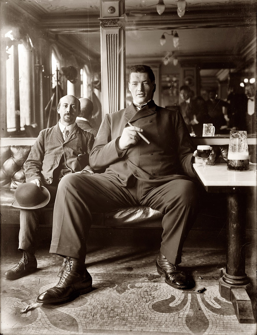 "Giant." Big man enjoying a cigar and glass of beer in a New York tavern circa 1908. View full size. George Grantham Bain Collection.