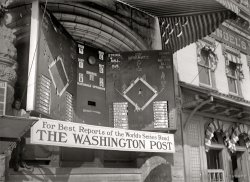 October 1912. Washington, D.C. "Baseball, Professional. Electric scoreboard." A close-up of the "baseball game reproducer" from the previous post showing results of the 1912 World Series between New York and Boston to crowds on a Washington street. Harris &amp; Ewing Collection glass negative. View full size.
Game 4This, specifically was Game 4, played on Friday, October 11.  Harry Hooper had just reached on a single, and any moment now Steve Yerkes will reach on a bunt misplayed New York's catcher Chief Meyers.  Boston would go on to win the game 3-1, and the World Series 4-3-1 (yes, there was a tie; game 2 was called in the 11th on account of darkness).
Nationals vs. OpponentsI love this. Love the design of the scoreboard, with the two different (hand-written?) fonts for the players' names, the light-up figures on the field, and the bell (right?) to be rung... when there's a hit, maybe? I also love the idea of a huge crowd "watching" the game this way. How much fun must it have been to be there!
The Mighty OzIgnore the man behind the scoreboard!
Old SmokeyIt's great to See Smokey Joe Wood up there.  His was a short career, but he was said to have been one of the best!
TV Off!  Use Your Imagination!Like Grandma Rose used to say, "TV off!  Use your imagination!"  
I still "watch" baseball in this manner (at work when I'm not investing company time on Shorpy.com), through MLB.com's Gameday.  It's still a decent way to "see" a ballgame!
Hmmm....Notice that it is "the World's Series"?
[Which is what people called it. - Dave]
An Early Version of MLB&#039;s GamedayThe technology changed but the design remains the same:

Fenway&#039;s InauguralThe 1912 season was also the first for the Red Sox in their new home - Fenway Park. 
The World&#039;s SeriesIt was called that because people still remembered that it was started by the New York World newspaper. In 1903 they set up the first championship series between the league champion of the established National League and the champions of the upstart American League (founded in 1901). The National League refused to compete in 1904 but came back in 1905. The series has been running ever since (well with the exception of the strike season of 1994). The series might be the last remembrance of the New York World even if most people aren't aware of it ("Why do they call it the World Series when only American teams play in it? The Japanese should be in it!")
Every city - maybe every newspaper - had one of these Electric Scoreboards, at least for the World's Series. I've seen a lot of references to them in the newspapers from the 1910s and '20s but this is the first time I've really seen what one looks like.
[According to the Baseball Hall of Fame and various "urban legend" authorities, the World Series has nothing to do with the New York World. - Dave]
Baseball Game ReproducerWashington Post Apr 20, 1910 


Fans Impressed With New
Baseball Game Reproducer

Thousands of excited fans stood for nearly two hours yesterday afternoon watching the Post's new electric baseball game reproducer, as it realistically reeled off play after play of the Nationals' last game of the double-header with Boston.
It was the unanimous opinion of the crowd that it was the finest exhibition of electrical scoreboard work that has ever been witnessed in this city, the only regret being the defeat of McAleer's men in the ninth inning.  Up to the fatal ninth, it looked as if the Nationals, with Johnson in the box, had the contest safely tucked away, and it was interesting to note the change of expressions on the faces as Stahl, the first man up, went out.  Four green lights sent the next batsmen to first on balls, and then the big bell told of two singles and a double, and before the contest was over Boston had sent three runners over the plate, and the game was won.
The board, which will reproduce every game the Nationals play away from hone, is a great improvement over the one which The Post used last season.  It is arranged to accommodate an unusually large crowd, and instead of one board as heretofore two will be in operation at the same time, the boards being set at an angle that it will be almost impossible for any on in the crowd to miss a play.
The lights indicating the various plays are so brilliant that they can be seen from the District building, and this alone is a big advantage to the crowd, especially those who are in the rear.  It is pitched just far enough from the street so that every play is visible, and the play is recorded on the board a fraction of a second after it is completed on the ground where the game is played.

Not the New York WorldApparently that origin of the name is actually untrue:
http://www.snopes.com/business/names/worldseries.asp
Board game?I have a vague recollection of a board game set up similar to this that was at my grandmother's house when I was a child. Given that my grandparents' generation would've been about 5 - 10 years old in 1912, I assume the game was based directly on these pre-radio electric scoreboards. By rolling dice or selecting cards (as I recall), you could play out a game by highlighting various positions and changing the players' names. 
Unfortunately, I was never much of a baseball fan, so it was all lost on me. Any of the baseball collectors here know what I'm talking about? I wouldn't begin to know how to google it.
ComplicatedI'd love to see how they controlled that thing! Are the lights, or did someone put up cardboard or something behind the cutouts?
[It looks to be boy-powered. Or at least boy-operated. - Dave]
Baseball in another ageI read about these gadgets in Cait Murphy's "Crazy '08," an account of the 1908 pro baseball season and World Series.  It's great to see a close-up, detailed photo of one of them.
Baseball ReproducerTo see one of these in action I recommend watching "Eight Men Out" to see a hand-operated indoor version. A couple of scenes are set in a hotel ballroom that's being used (in 1919, the last season before the first games broadcast on radio) to translate pitch-by-pitch telegraph messages into graphics on a smaller board that looks very much like the outdoor board above. A man dressed like a headwaiter uses wooden dowel or pointer to move a "player" figure up a slot that representing the basepath.  
Of course there are at least 600 reasons to watch "Eight Men Out."  
Game 7It is actually Game 7.  When looking at the lineup in the picture, Devore is playing RF.  In the three games with the same pitching matchups, Devore plays RF in Game 7 only -- and LF in the others.
(The Gallery, D.C., Harris + Ewing, Sports)