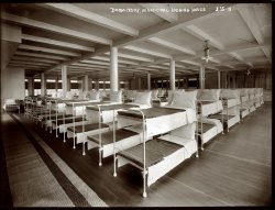 February 1909. Men's dormitory at the New York municipal lodging house. 8x10 glass negative, George Grantham Bain Collection. View full size.
Sleep Number"Any man not in his bunk at eight will spend a night in the box. There is no smoking in prone position in        bed. To smoke you must have both legs over the side of your bunk. Anyone caught smoking in prone position will spend a night in the box. You get two sheets. Every Saturday you put the clean sheet on the top, the top sheet on the bottom and the bottom sheet you turn in to the Laundry Boy. Any man who turns in the wrong sheet spends a night in the box. No one will sit on the bunks with dirty pants on. Any man sitting on a bunk with dirty pants will spend a night in the box."
- Carr the Floorwalker, "Cool Hand Luke"
Paging Lewis HineWell, the place looks immaculately clean.  Lewis Hine would have loved it.  Wonder if it smelled like formaldehyde?
Ikea for the ItinerantThe Dormitory is a remarkable foreshadowing of the Minimalist aesthetic and a number of other 20th century design trends.
On another note, let's not be dissing LWH, people. You would surely be forgiven if you found his work just a trifle tendentious and I, for one, am not overly fond of didactic art, but Hine clearly had another agenda and art was probably just an incidental. I don't know to what degree Hine considered himself an artist (or not), but it seems clear that his commitment to documenting child labor was nothing short of heroic. By way of illustration, the inquisitive may wish to have a look here.
Dave (or any of you kids in the peanut gallery), do you happen to know of a good biography of Hine? I think it would be difficult to spend any time around Shorpy and not be at least mildly curious about the man.
On a more general note, there is not a day that goes by that I don't appreciate the efforts of the photographers whose work populates these pages and the yeoman service done by Dave and Ken and such others as may populate the Shorpy ranks. The work done in presenting these photos (choice, editing, captioning, &amp;c.) is the very definition of 'value added'. The window that this site provides on the past is of incalculable value. As some of the Anonymous (and otherwise, myself included) Tipsters continually demonstrate, we need a lot of help in seeing past our 21st century prejudices.
Faux PasI neglected to mention Joe Manning! And here I am asking about Lewis Hine... duh.
Thanks, Joe.
Hine BioI saw an excellent documentary last week on the Documentary channel called "America and Lewis Hine." It is being rebroadcast on 03/18/08, 04/02/08, 04/03/08, and probably more, because they replay programs often: http://www.documentarychannel.com/schedule/index.php
NYTimes review.
And there is a VHS copy for sale on Amazon.
Too bad I'm posting this relative to someone else's photo.
Hine BioThis is Joe Manning. The best three books I've read on Hine so far are:
"Kids at Work: Lewis Hine and the Crusade Against Child Labor," by Russell Freedman and Lewis Hine
"America and Lewis Hine: Photographs, 1904-1940," by Walter Rosenblum, Alan Trachtenberg, Naomi Rosenblum, and Marvin Israel
"Lewis Hine in Europe: The Lost Photographs," by Daile Kaplan
Fascinating Light FixturesAny information on them?
(The Gallery, G.G. Bain, NYC)