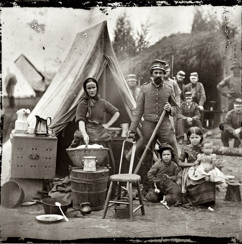 From 1861, a second look at these Northern infantry campers -- and our first glimpse of their puppy. "District of Columbia. Tent life of the 31st (later, 82nd) Pennsylvania Infantry at Queen's Farm, vicinity of Fort Slocum." View full size. Wet-plate glass negative, left half of stereo pair, photographer unknown. This has a lot in common with the pictures Dorothea Lange would be taking 75 years later of Dust Bowl migrants in the agricultural tent camps of California.
Library of Congress annotation: Princess Agnes Salm-Salm, wife of Prince Felix of Prussia, who served with the Union Army, observed in January 1862 that the winter camp of the Army of the Potomac was "teeming with women." Some wives insisted on staying with their husbands, which may have been the case with this woman, judging by her housewifely pose alongside a soldier, three young children, and a puppy. In addition to taking care of her own family, she may have worked as a camp laundress or nurse. Some women who lacked the marital voucher of respectability were presumed to be prostitutes and were periodically ordered out of camp. Only gradually during the four years of the war, and in the face of unspeakable suffering, were women grudgingly accepted by military officials and the general public in the new public role of nurse.
