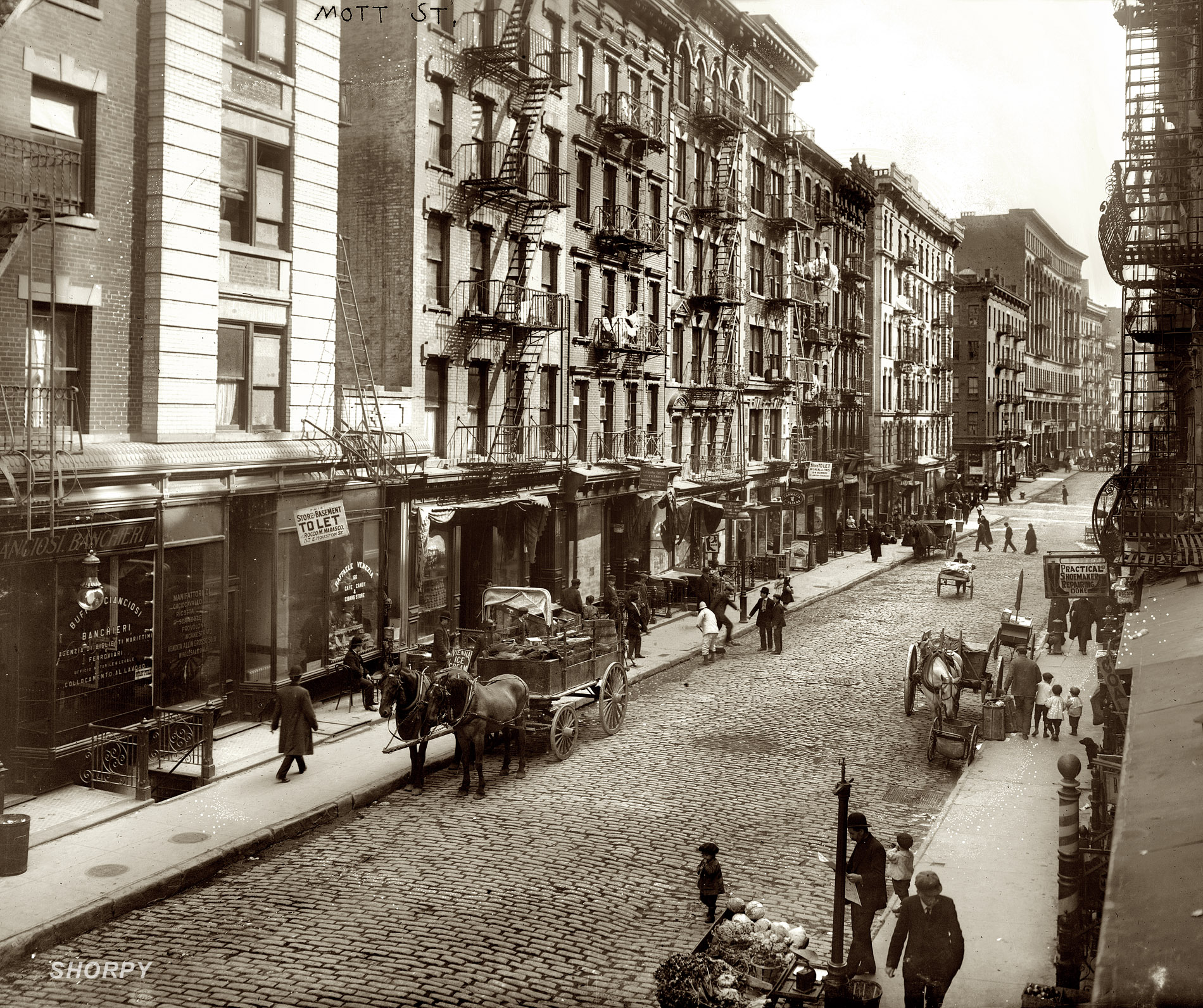 1910. Mott Street in New York's Little Italy, now Chinatown.  At the left, 166 Mott (Raffaele Venezia Cafe) is now Face to Face Skin Care. Google Street View. 8x10 glass negative, George Grantham Bain Collection. View full size.