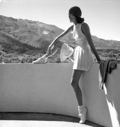 A woman sitting on a wall looks at the mountains behind her. The image is by fashion photographer Toni Frissell and was published in Harper's Bazaar in February 1947. View full size.