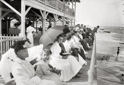 New Jersey circa 1910. "At Casino, Belmar, Sunday." There was some controversy over whether the beaches at the Jersey Shore resorts should be open on Sunday. 5x7 glass negative, George Grantham Bain Collection. View full size.
What&#039;s the Point?Interesting how the lines of perspective conveniently converge on the boy leaning on the railing. By design or fortunate happenstance? Don't know if the photographer was being clever or just lucky. Either way, it anchors the shot to the point (pun?) where it is difficult to keep your eye from gravitating to his noggin. The depth of field is fantastic as well; there are more details that can be seen than one would expect.
Morality 1910 styleI am most impressed by the expressions, each of which is in response to the photographer. The lady in the foreground looking straight ahead as if to say, "I don't want you, so am going to ignore you." Next is the very interested little girl. Beyond her is a brother-sister pair (faces nearly identical in their features). She is not too thrilled to have her photo taken. He's really, really annoyed. And some of those naughty, naughty Victorian women have left two pair of shoes on the boardwalk. One has even removed her socks too. But at least those hussies had the decency to hide their feet under their skirts. It may be of questionable morality to go to the beach on a Sunday, but show your feet in public -- never!
Finally, A differenceIf this were a modern photo, almost every one of these people would have a beverage in hand. I finally noticed something that was quite different between then and now. Of course, it ws thought rude to eat/drink/smoke "on the street" then.
(The Gallery, G.G. Bain, Sports)
