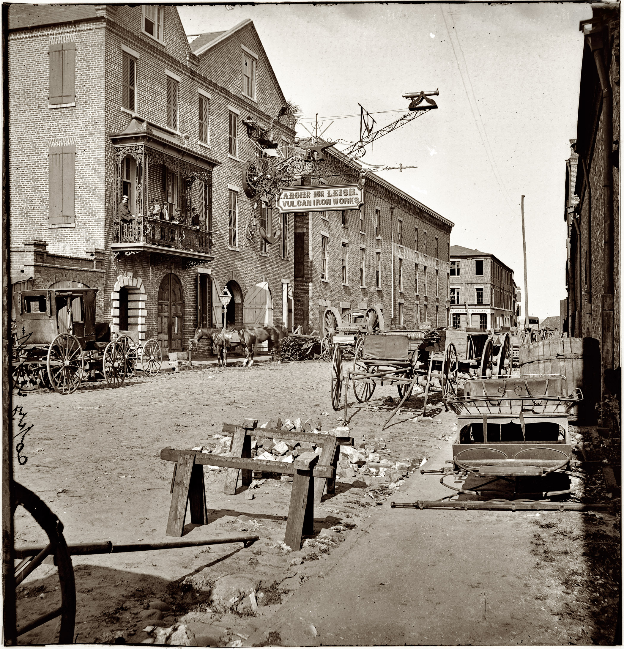 1865. Charleston, South Carolina. Archibald McLeish's Vulcan Iron Works on Cumberland Street. Left half of glass-plate stereograph, from photographs of the Federal Navy and seaborne expeditions against the Atlantic Coast of the Confederacy, 1863-1865. View full size. Note the unusually elaborate sign, as well as what seem to be the giant wheels of an artillery carriage.