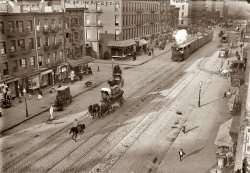 A detailed circa 1910 Manhattan streetscape of rail cars at West 26th Street and Eleventh Avenue, known as "Death Avenue" for the many pedestrians killed along the New York Central's freight line there. View full size. Removal of the street-level tracks commenced on December 31, 1929. 5x7 glass negative, George Grantham Bain Collection. Update: Click here for the largest version.
A Freight TrolleyI think this is one of my favorite photos ever.  There's so much going on here that is representative of the time that I could spend hours scrutinizing it.  I'd never even heard of there being freight trolleys that would rumble down city streets (I know, I need to do my homework).  All the activity and storefronts and normalcy of it all.  Simply incredible.
"How do I get to the Susquehanna Hat Company?"
Re: Freight TrolleyHere's a closeup of the engine. The coal seems to be in a bin on the front. Bain took several photos of this rail line and the freight cars. I'll post some more in the coming days. Any railfans out there who can tell us more about the 11th Avenue line?

What&#039;s she holding?Out of all the details in this picture, there is one that has drawn my attention.  On the left side of the street, about in line with the front of the train, there is a woman holding something white.  Can someone with a better monitor tell what that is?  I'm thinking large dog (though I think it's unlikely that a dog that large would be carried--unless maybe it was scared by the train?) or squirming child, or possibly a massive sack of flour (not that likely, I admit.)  
Anyone?
[Looks like a bundle of packages wrapped in paper. - Dave]
Freight Trolley?I don't think so, at least not by most definitions. A trolley draws power from overhead lines and I can't see any power lines above the tracks or the necessary connecting wires (and their poles) to keep it in place. I do see a steam engine [Coal-powered. See photo below. - Dave] of a fairly specialized type and in the distant background a line of freight cars crossing the street. Given the proximity of the location to the Hudson River (it's near what is now Chelsea Docks) it wouldn't surprise me if this wasn't a New York Central spur line to connect the docks to a main line, in the period before most of the rail traffic in New York City went underground. There is a street car in the shot, but I'm guessing that it's a horse car (pulled by at least one horse).
What I find really interesting is that there's not a motor vehicle in sight, just horses, and the sheer amount of what the horses left behind (to put it euphemistically).
&quot;Freight Trolley&quot;The engine, as noted below, is clearly not a trolley.  It appears to be a "steam dummy," a small locomotive, largely enclosed, often looking like a streetcar so as not to frighten the horses.  A conventional locomotive, even a small one, with large driving wheels and flashing connecting rods, would certainly frighten the animals.
Mounted FlagmanI guess the guy on the horse on the foreground is also a mounted flagman... he is preceding the steam train to protect pedestrians!
Remember... "2000 killed in ten years" on the Death Avenue (Eleventh avenue)!
-----------------------------------------
Funimag, the web magazine about Funiculars
 http://www.funimag.com
Funimag Blog
 http://www.funimag.com/photoblog/
Guy on the roofDid you see the guy on the top of the roof of the third wagon? I am wondering what he is doing! Maybe watching pedestrians!!!

Incontinent horse!Did you see the incontinent horse?!!! Gash...! What a big river!!! That picture is really fantastic!!
Re: Guy on the RoofThe man on the roof is a brakeman.  Riding a car roof is better than hanging on a ladder on the car side.
Horse-drawn tramJust to the right (our view) of the "train" is a horse drawn tram car being drawn along the track in the opposite direction.
BrakemanPlease note that there are no brake hoses on the locomotive. All handbrakes, so the brakeman rides on top because the staff brakes are on the car tops. to stop the train the engineer signals the brakeman and he starts ratcheting down the handbrakes
How fast?I'm wondering just how fast these trains were barreling through the street to hit so many people?  If they were being preceded by a guy on horseback they couldn't have been gong all that fast.  And yet people still did not notice them coming?  How does one not hear a steam locomotive?
Tank DummyPerhaps the locomotive is one of these (scroll down to
the bottom of the page):
http://www.northeast.railfan.net/steam22.html
The sheer amount of detail in this is incredible.E.g. the kids' chalk scrawls on the sidewalk.
I'd imagine that a lot of the deaths occurred at night or in bad weather.
My favorite partMy favorite part is the kid running down the sidewalk on the lower left.  Perhaps he's trying to outrun the train?  He reminds me of the drawings of Little Nemo.
[Lower left? Or right? - Dave]
The beer wagonIncredible photo!  The detail is fantastic.  I like the beer wagon (wishful thinking?) in front of the train.  I am just amazed....
CrutchesWhat about the guy on crutches on the right. I wonder what the story is behind that.
26th and 11thI went and looked up the intersection on Google maps, and the whole right side is a parking lot now.
Triangle Shirtwaist FireThe worst factory fire in the history of New York City occurred on March 25, 1911, in the Asch building, where the Triangle Shirtwaist Company occupied the top three of ten floors. Five hundred women, mostly Jewish immigrants between thirteen and twenty-three years old, were employed there. The owners had locked the doors leading to the exits to keep the women at their sewing machines. In less than fifteen minutes, 146 women died. The event galvanized support for increased safety in the workplace. It also garnered support for labor unions in the garment district, and in particular for the International Ladies' Garment Workers' Union.
Much material was provided by several websites, but two in particular I want to call attention to, the first for an overall exceptionally presented look back at this tragedy and a stunning presentation of the labor movement. Truly a brilliant multimedia presentation.
The Triangle Factory Fire – Presented by The Kheel Center, Catherwood Library, ILR School at Cornell University.
and National Public Radio ...
I can not recommend those two sites too highly. They are top-notch.
And on YouTube, The Cloth Inferno.
11th Avenue TrainBeneath the "dummy" shroud, it's actually a two-truck Shay locomotive, a type of geared power popular on many logging and industrial operations with sharp curves and steep grades.
High LineThis rail line was replaced with an elevated line that entered the warehouses of the west side on their upper floors.  It continued to be used into the early 1980s mostly for boxcars of produce.  The boxcars shown are refrigerated for perishable items. The roof hatches are for loading ice into bunkers at the ends of the cars.
The elevated rail line still exists but is now owned by the city which is rebuilding it into an elevated linear park in Manhattan's Chelsea district.
11th Ave trainIf you look at the largest version you can see that it says 11 on the front which would make this an 0-6-0, class B-11. The Shays also show the offset boiler. Great photo.
26th and 11thWest 26th &amp; 11th is the location the fabulous old Starrett Lehigh Building, a block-long warehouse looking like a stylized ocean liner, with train tracks from the pier leading right into the building and up the freight elevators. Its time was past before it was even finished in 1931 as  the trucking industry eclipsed rail freight. Funky old place to wander around if you ever get the chance.  
26th &amp; 11thThe right side of 11th Ave &amp; 26th St will be the terminus of the 7 Train extension from Times Square.  (last station will be 11th Ave and 34th) . They are currently boring down to the bedrock.
NY Central dummy engine>> Beneath the "dummy" shroud, it's actually a two-truck Shay locomotive
It seems the NY Central Shays weren't built until 1923-- so looks like he's right about the engine being an 0-6-0 beneath the dummy housing.
N.Y. Central ShayA city ordinance required that a horseman precede the rail movement, and that the locomotive be covered to look like a trolley car so as not to frighten horses. When the line was elevated it was electrified, I believe with locomotives that could also run on batteries to access trackage that had no overheard wires. At that time the Shay locomotives were put to use elsewhere on the New York Central system. Here is a photo, from my father's collection, of one of the Shays in service near Rochester, I believe. The spout on the left is not part of the locomotive but is on a water stand behind it.
Not The Sound of Silence!Just try and imagine the sounds here! The shod horses clomping down the brick street. The wagons creaking along as the wheels roll on the bricks and dirt. The various bells (church, train, etc) pealing, the subtle sounds of conversations and pedestrian footsteps, the whisk of broom bristles as the street is cleaned! Much preferable to the honking, boom-boxing, brake-screeching, muffler-rapping scenarios we endure today!
10th AvenueAnother pic shows what 11th Avenue north from 26th St actually looked like; someone mislabelled this negative of 10th Ave.
Building Still ThereAccording to a post here, this is actually the intersection of 10th Ave and W 26th Street.  I looked up this intersection on Google Maps and it appears that one of the buildings in the old photo is still there.  It's way down the street..behind the train, the 3rd building from the end on the left side of the street. (The windows look like there is a white stripe connecting them).  I think that is the same building on the northwest corner of the intersection of 10th Ave and 27th Street. Just thought I'd throw that out there :)

29th StLooks like you're right, that bldg is still there, but it's on the NW corner of 29th St and 10th Ave. In the Google streetview it's about a twin of the bldg at 28th St.
At the left edge of the Shorpy pic you see 267 10th Ave, which means the engine is about to cross 26th St. The train moved from the yard onto 10th Ave at 30th St.
Pic of 11th Avenue https://www.shorpy.com/node/12859
(The Gallery, G.G. Bain, Horses, NYC, Railroads)