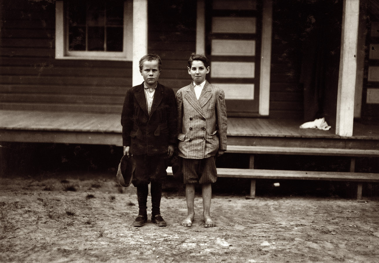 November 1914. Roanoke Rapids, North Carolina. Rosemary Manufacturing Co. Two violations. Simon Birdsong, left hand boy. "I'm about 12." His mother said: "He's old enough to work all right," but the boy admitted that she had to sign up that he was older than he was. He appears to be 10. Has had job doffing for several weeks. Could not write his own name. Has had no schooling after the 1st grade. Wylie Haw (right hand boy). Mother says he is 12 years old now. Been working 1 year. She is a widow. Photo and caption by Lewis Wickes Hine. View full size.