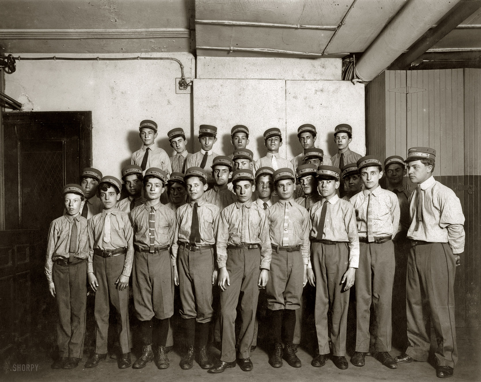 New York, July 1910. "A typical group of messengers at Postal Telegraph Company's main office, 253 Broadway. During hot weather they wear these shirtwaists. (A Suggestion for the other companies.)" Photograph and caption by Lewis Wickes Hine. Library of Congress. View full size.