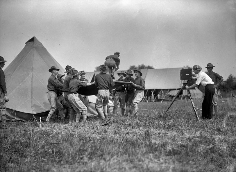 1915. "National Guard of D.C. -- Field tactics." Nothing like a blanket toss to confuse the enemy. Note the Hollywood type behind the movie camera. Harris &amp; Ewing Collection glass negative, Library of Congress. View full size.
