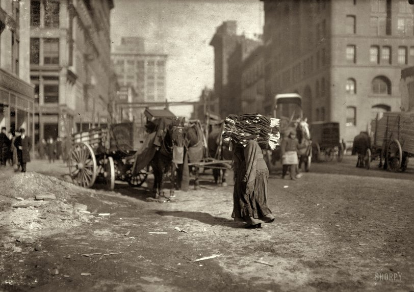 New York, February 1912. "The breaking point. A heavy load for an old woman. Lafayette Street below Astor Place." Photo by Lewis Hine. View full size.
