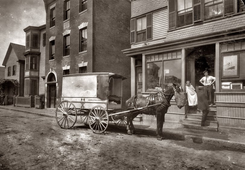 August 1912. "The wagon that delivers Home Work to Somerville, Massachusetts. The owner of the wagon (who is not the driver) is O. H. Brown, 27 Main Street, Reading. These wagons (about 4 in all) are worked on commission, not owned by factory." ("Home work" here meant pre-cut cloth patterns ready to be sewn into various articles of clothing.) View full size. Photograph by Lewis Wickes Hine. Note the curious tassels hanging off the horse. (Answer: It's a fly fringe.)