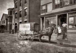 August 1912. "The wagon that delivers Home Work to Somerville, Massachusetts. The owner of the wagon (who is not the driver) is O. H. Brown, 27 Main Street, Reading. These wagons (about 4 in all) are worked on commission, not owned by factory." ("Home work" here meant pre-cut cloth patterns ready to be sewn into various articles of clothing.) View full size. Photograph by Lewis Wickes Hine. Note the curious tassels hanging off the horse. (Answer: It's a fly fringe.)
TasselsMaybe to keep flies away? just a wild guess.
[Yes, or maybe to wick the sweat off. - Dave]
Titanic?Who can ID the ocean liner in the window.

Not the TitanicThe Titanic was a 4 stacker vessel. There are only two on this ship. Could have been one of any number of other ships that brought a steady stream of immigrants to America during that period. Three of my own grandparents came here that way.
1905The house after the lot has a stone marked 1905, would that be the date it was built or the address?
[Year. - Dave]

tasselsTo keep the flies off -to combat the dreaded mosquito-born equine diseases.
Guy in the tie.I just love the guy in the white shirt and tie with his hands on his hips.  You can just tell what he's thinking, "Hmm, what's that young fellow with the queer looking box doing out there in the middle of the durn street?  He's looking to get run over, that's what he's fixin' to do..."
If those were for flies IIf those were for flies I wonder how effective they were.
How ever did horses survive without humans to drape strings on them and cover their snout with a feedbag.
[It's called a fly fringe. All the fringes need to do is move back and forth a little as the horse moves to do their job. - Dave]
HomeworkI swear, Elmer...... that there horse eats better'n I do.
(The Gallery, Horses, Lewis Hine)