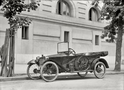 Washington, D.C., circa 1914. "Kar Nation." One of four photos of this odd-looking auto taken from various angles. Harris &amp; Ewing glass negative. View full size.
Look Ma!  No DoorsNot on the street side, anyway. Nobody entered or exited there. Too many road apples and too much mud. Left side doors gained popularity later, in the mid 20's.
Was it Pink?The Car-Nation was a lightly built cyclecar produced in Detroit in 1913 and 1914. This one is the four seater tourer and would have cost $520.
Interesting in that is is very similar to the French Marlborough cyclecar (1906 t0 1926) except that the Marlborough had a rounded-front to the radiator.
Curbside AccessI'm assuming there's a door on the curbside of the car, since there doesn't appear to be one on the side facing the camera. Was it common on early cars to have no driver's side door?
Before its timeSort of the AMC Gremlin or Pontiac Aztec of the era I suppose. 
Car-NationThought I remembered that as a make of car. Try Wikipedia under "Car-Nation" for a picture of a restored one. They were built 1913-1914 in Detroit, Michigan, by the American Voiturette Company.
Masonry wallsThe car appears to be parked on H Street NW just east of 13th. The building behind it is the old Masonic Temple, now the National Museum of Women in the Arts.
CanisterWhat is the canister shaped thingy on the running board?
[Acetylene gas reservoir for the headlights. - Dave]
Mass Market AttemptCycle cars were an attempt to reach the mass market by producing small, lightweight cars in a period when the majority of automobiles were large and expensive. 
They were pretty much supplanted by the Ford Model T - a full size car at a mass market price. They remained a fringe market well into the '20s. The market was slightly revived by the Crosley and European microcars after WWII.
No DoorsOne reason many cars of these early times had no streetside doors was because the hand brake and various other appurtenances would have blocked them. I believe some Model T Fords sported this "feature."
[Another reason: Cheaper to build. - Dave]
Current Car-NationFound this article about a restored one.
Deep ThoughtsAlthough I prefer car designs from the 1960s on, I must say this is a great looking car. Nice clean design. Wish I had it in my garage! Every time I see a photo on Shorpy, I get confused in all sorts of time and place thoughts, difficult to grasp what it really means -- 10 years, 20 years, 50 years. Imagine hundreds of years. People then didn't think of computers as mobile phones as missing tools. They thought they were living in times of progression and they were, too. They were as comfortable in their homes as we feel now, it's all relative. Was life better then or is it better now?
(The Gallery, Cars, Trucks, Buses, D.C., Harris + Ewing)