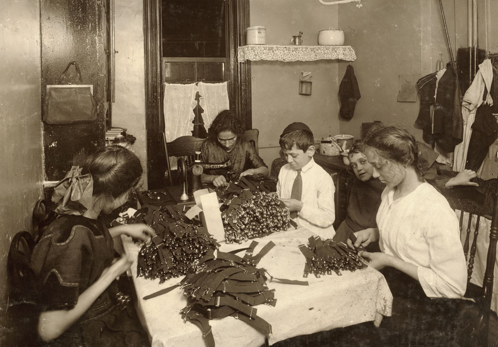 A Jewish family works on garters in the kitchen of a New York City tenement home. Photo by Lewis Wickes Hine, November, 1912. View full size.