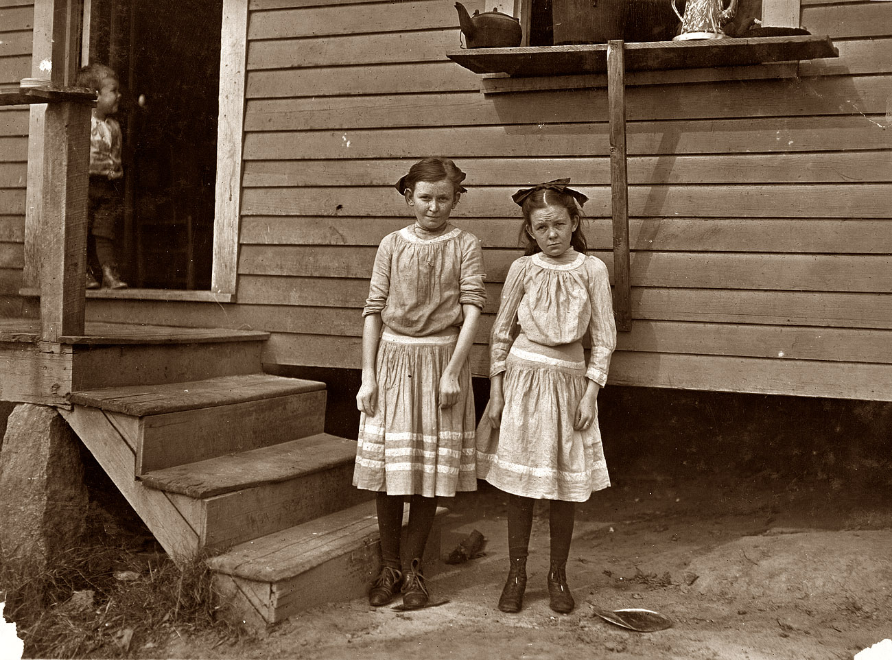 November 1908: Gastonia, North Carolina. Lacy, 12 years old, and Savannah, 11. Have worked two years. Father said "The little one is a crackerjack on spinnin', at least so the boss says. She ain't satisfied unless in the mill. The oldest one isn't so good at it. Not as quick." (Note the tense, serious looks on the younger. Older one more like a real girl.) View full size. Photo and caption by Lewis Wickes Hine.