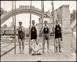 "Potomac Boat Club Sema [?] Sig," 1921, with the Key Bridge under construction in the background. View full size. National Photo Company Collection.
Potomac Boat ClubThis is upriver and from the dock of P.B.C.  I have been a member of Potomac Boat Club for over twenty years, they have been around since 1869.  The address is 3530 Water Street, Washington D.C. 20007.
Upriver?Looks like this shot was taken upriver of the Key Bridge, so it might the Washington Canoe Club dock http://www.washingtoncanoeclub.org/
They have a beautiful old building which is a landmark on the Georgetown waterfront. We often canoe this stretch of the Potomac, and it's a great way to see the city.
socksWhat's with the socks? Floppy socks, socks with a hole in the toe -- and those socks on the guy who's sitting down, which don't seem to be socks at all.
Potomac Boat ClubIt's definitely PBC. It isn't far enough to be the canoe club.  This is interesting, I had no idea that the boathouse was older than Key Bridge.
Aqueduct BridgeThe old Aqueduct Bridge was torn down when the Key Bridge was constructed. The linked photo shows what looks like Potomac Rowing Club's building at the D.C. abutment. So it appears it does predate Key Bridge.
Potomac Boat ClubThis is definitely PBC, which sits up against the old aqueduct abutment. The star is their insignia.
Key BridgeJust returned from a stay at the Key Bridge Holiday Inn. We could see the old abutment and dock with star on it from our balcony, and when I got home I googled to see what it was and spent an enjoyable hour or so reading up on the history of the old aqueduct and the general neighborhood. How cool to see this now, knowing a little about the area.
(The Gallery, Boats & Bridges, D.C., Natl Photo)