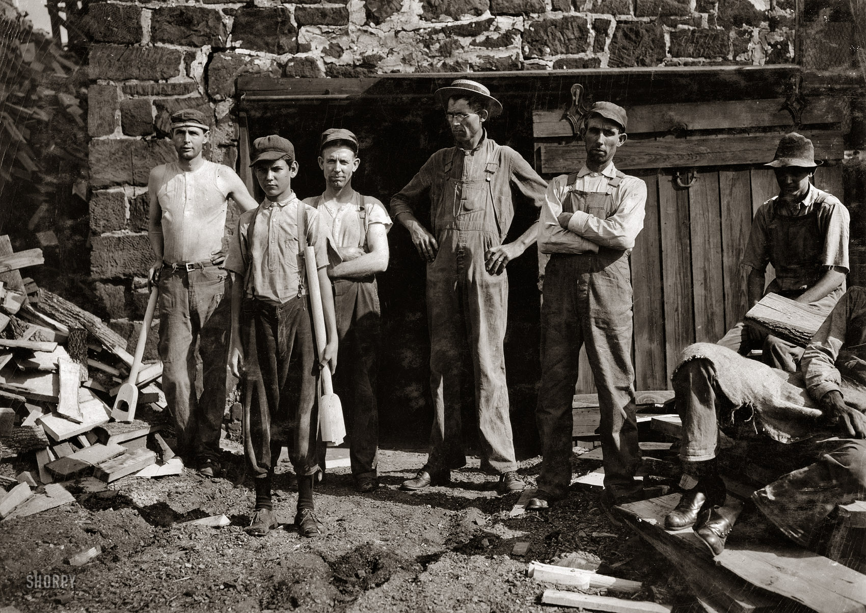 September 1913. Denison, Texas. "Group outside Pittman Handle Factory. A 15-year-old boy operating a dangerous boring machine at which he said a boy recently bored half his hand off. To operate this machine (which bores a large hole in the spade handle) the boy has to throw his whole weight onto the lever which pushes the handle (and himself) up against the unprotected borer. A slip might easily result fatally. Boy earns $1.65 a day. This factory has a number of unprotected belts and dangerous machines. One other boy, about the age of this one, was doing all kinds of work, taking away the handles from a huge rip saw, etc., and constantly exposed to danger." Photo by Lewis Wickes Hine. View full size.