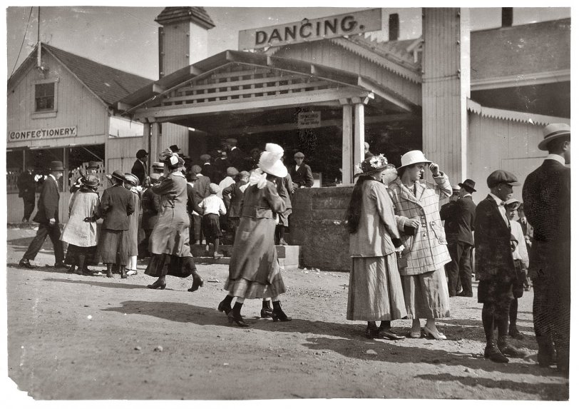 June 1916. Sandy Beach near Fall River, Massachusetts. "Two girls in foreground about 15. Mr. Tebbutt says dance hall bad conditions. Penny picture machine attracting crowds." View full size. Photograph by Lewis Wickes Hine.