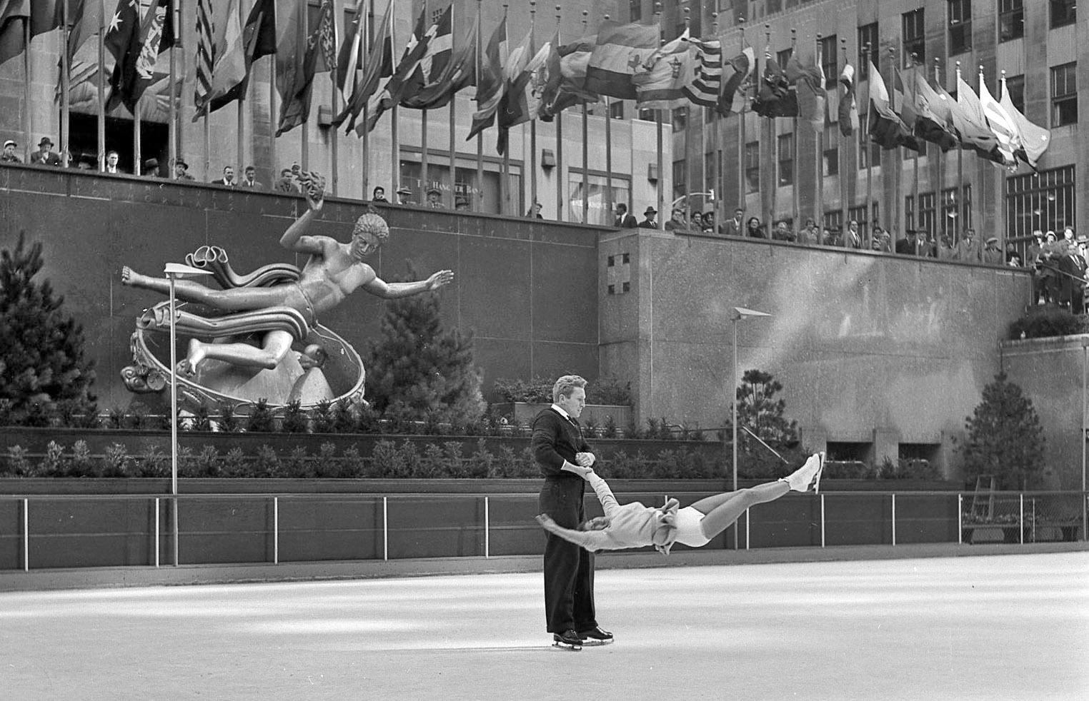 My grandfather took this photo of professional skaters putting on a show at New York's Rockefeller Center rink in November, 1954. I think the gesture of the sculpture with its arms upheld really works with the skaters. View full size.
