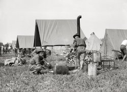 1915. "National Guard of D.C. cooking." Just what is it that makes a fried egg taste so much better out of doors? Harris &amp; Ewing glass negative. View full size.
Colonial Beach, Va.


Pick Guard Camp Site

After several weeks filled with much guessing on the part of the District national guardsmen in general and much search on the part of the commanding general and his aids, Colonial Beach, Va., has been picked as the camping ground for the annual maneuvers of the infantry branch of the guard, it was announced yesterday.  The encampment is to begin August 16 and continue to August 28.  
There have been several places under consideration, ... The camp sites usually investigated each year are at Harpers Ferry, Virginia Beach, Frederick, and other places within easy distance of Washington.

Washington Post, Jul 21, 1915



Guard Ready For Trip
Embarks Tomorrow for Colonial Beach Encampment.

Every officer and man in the District National Guard is eagerly anticipating the events of tomorrow morning.  Everything is now ready for the embarkation for Colonial Beach, where the guardsmen will put in two busy weeks of real soldiering.
...
Subsistence and bagage, was in the hands of the quartermaster's and the commissary departments.  The quartermaster, Maj. Robbins, has had a very busy time.  All the baggage had to be on the docks by Thursday last, the rest of the time it was all being loaded aboard the St. Johns by a force of civilian labor, under the charge of Maj. Nevils and a staff of commissioned  and noncommissioned officers.
...
The guard while in camp will have its food provided by the subsistence department.  Only enlisted men, however, will be issued rations.  Each company, band and separate organization will have its own kitchen and equipment.  The encampment order provides that enlisted cooks shall be used whenever practicable, although civilian cooks will also be allowed.  The necessary mess arrangements for the various commands will be made by the commanding officers.

Washington Post, Aug 15, 1915 



District Boys Will Get a Taste of Real Soldier Life.

...
The first full day in camp will be a busy one. The bugle will sound at 5:15 a.m.  From that time to the first call to drill at 7 o'clock, the camp will be in an orderly whirlwind.  The first important thing to attend to will be breakfast, and many citizen soldiers will taste camp fare for the first time.  After breakfast, the camp must be carefully policed, or, in civilian lingo, "cleaned up."
...
Drills end at 3 o'clock.  After that until 5 o'clock, the men may do as they like.  There probably will be a rush for bathing suits the first thing, and then a race to the beach.  The parade or review will start at 5:30 o'clock.

Washington Post, Aug 16, 1915 


Oeufs AlfrescoIt's the leaf lard and/or bacon drippings. Magnifique!
(The Gallery, D.C., Harris + Ewing)