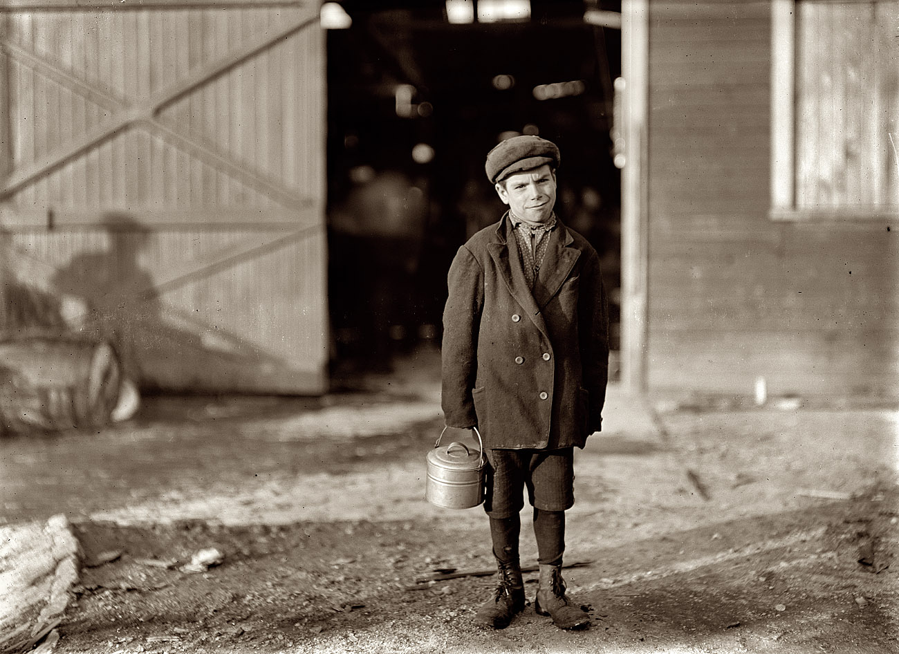 October 1908. Fairmont, W.Va. Monongah Glass Co. Jo Before, a glassworks boy going home, 5 p.m. He says he is 12 years old, and has been at it one year. Is a "ketchin-up-boy" for 70 cents a day; says glass business is all right. Asked if he was going to be a glassblower when he grows up, he said, "Sure!" Goes to school; asked if he had to, he answered "Don't unless I want to"; asked why he went then, said, "Want to learns something." Photograph by Lewis Wickes Hine. View full size. 