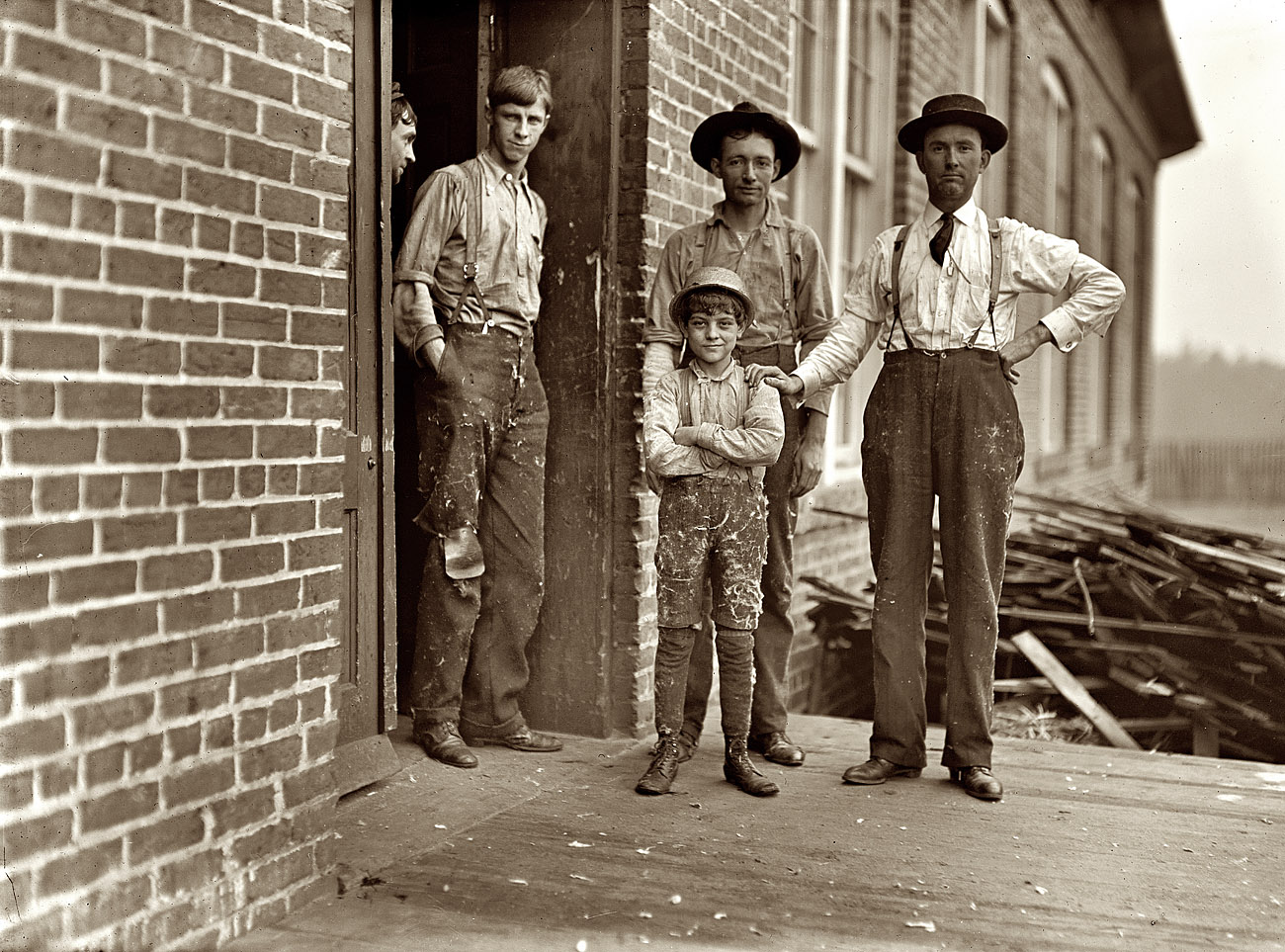 January 1909. Macon, Georgia. "This boy has worked in Payne Cotton Mill for 2 yrs. Runs four sides and earns 52 cents a day. Overseer has hand on boy's shoulder. He said this mill made 70% profit last year and expects to make 100% this year. Owned by Bibb Mfg. Co." View full size. Photo by Lewis Wickes Hine.
