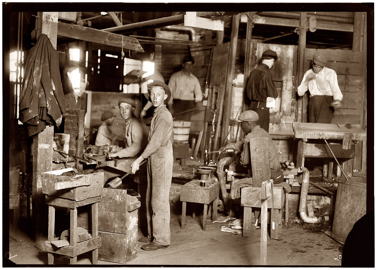 November 1909. Cumberland Glass Works at Bridgeton, New Jersey. A young "holding-mold boy" is seen, dimly, to the left [little kid toward the back]. Negroes, Greeks and Italians are being employed in many glass houses. View full size. Photograph and caption by child-labor reformer Lewis Wickes Hine.
