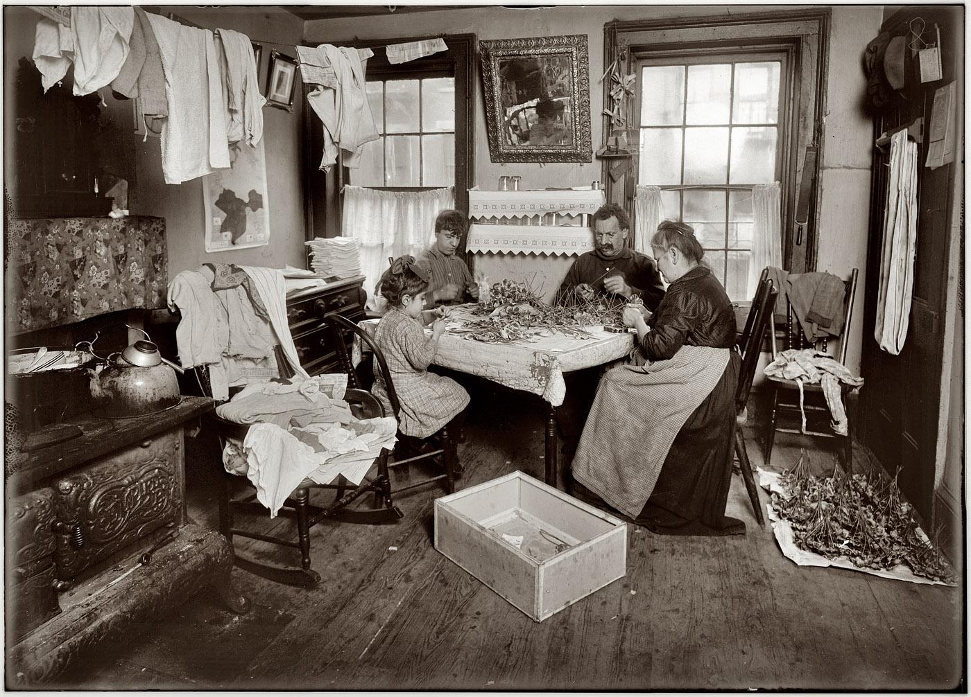 January 1912, New York City. View full size. To the untrained observer this might be a pleasant domestic scene; to the eye (and lens) of social reformer Lewis Hine, however, it is a diorama of decadence and moral decay, with peril lurking in every detail. The object of his ire here is the use of child labor in tenement home work, specifically the assembly of artificial flowers: "Julin, a 6-year-old child, making pansies for her neighbors on top floor (Gatto), 106 Thompson St. They said she does this every day, 'but not all day.' A growler and dirty beer glasses in the window, unwashed dishes on the stove, clothes everywhere, and flowers likewise." Photo and caption by Lewis Wickes Hine. (NB: Growler = beer pitcher.)
