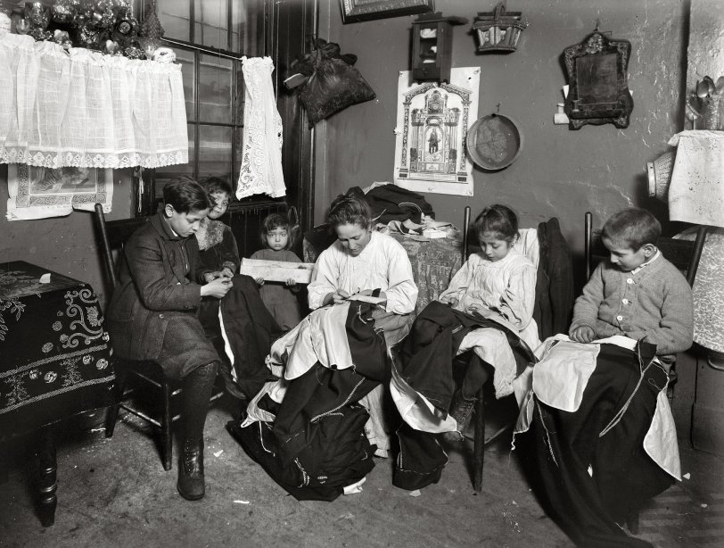 New York City, January 1913. "1 p.m. Family of Onofrio Cottone, 7 Extra Place, finishing garments in a terribly run down tenement. The father works on the street. The three oldest children help the mother on garments: Joseph, 14, Andrew, 10, Rosie, 7, and all together they make about $2 a week when work is plenty. There are two babies." View full size. Photograph by Lewis Wickes Hine.
