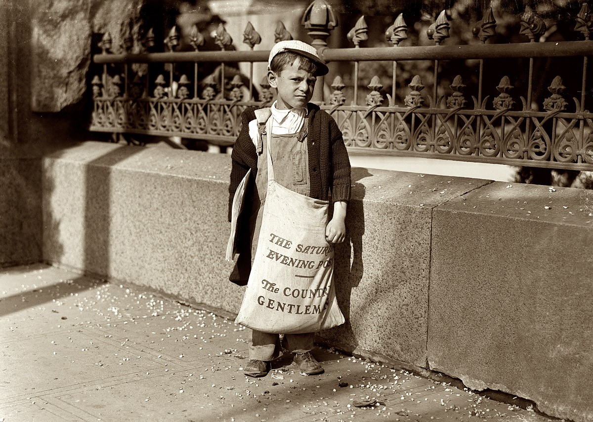 May 1915. Sacramento, California. "Freddie Kafer, a very immature little newsie selling Saturday Evening Posts and newspapers at the entrance to the State Capitol. He did not know his age, nor much of anything else. He was said to be 5 or 6 years old. Nearby I found Jack, who said he was 8 years old, and who was carrying a bag full of Saturday Evening Posts, which weighed nearly half of his own weight. The bag weighed 24 pounds, and he weighed only 55. He carried this bag for several blocks to the [street]car. Said he was taking them home." Photograph and caption by Lewis Wickes Hine. View full size.