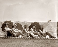 "Lansburgh bathing girls" in 1922 near Washington, D.C. Girl on the right: Iola Swinnerton. View full size. 4x5 glass negative, National Photo Company.
IolaThe woman on the right is fantastic. What a beautiful face!
Famous GroupieI think the woman on the right looks exactly like Pamela Des Barres, which is not necessarily a compliment.
More IolaIola is OK in this photo, but I like her even better in this one.
[She's also here and here and here. Who can tell us what became of lovely Iola? - Dave]
Iola&#039;s friend......the girl second from the right... She is in a number of these 'bathing beauty' pics, too, and always right next to Iola.  They must have been best friends, or maybe even sisters! :)
IolaAccording to the SSDI there are at least 30 women who were issued Social Security cards in Wash. D.C. named Iola who would have been between the ages of 16 and 25 in 1922. 
An SSDI search for "Iola Swinnerton" turned up bupkis.  So she either married or she is still alive and approximately 100 years of age.
 I didn't even bother checking Maryland or Virginia.  Apparently Iola was a very commmon name in the South and Midwest at the turn of the 20th century.
IolaI found the same Washington Post article and it gives the other girls names as Mary Lee, Thelma Spencer, Hattie Spencer and Julia Cunningham.
The winners were models for Lansburgh &amp; Brothers (which I assume was a department store or dress shop) and the photos are from a "Style Show" held at the Tidal Basin
[Yes, Lansburgh's was a big department store in Washington. - Dave]
Elusive IolaI haven't found a great deal more, but I did discover some newspaper clippings about her beauty contest winnings via Ancestry.com, and if it helps to narrow your search any, in 1920 she was described as an 18-year-old restaurant cashier from (and working in) Washington, D.C.  
Exquisite Clothing DetailI adore the headpiece on # 5 on the right. I want to steal that idea for a costume. It would play beautifully today.
So happy!I love the pictures from the 1920s! The people always look so happy. Granted, these girls just won a bathing suit contest, so of course they'll be happy, but in every 20s picture I've seen everyone looks so happy and carefree, like they can do anything and be anything in the world. Just love it thank you for this site!
Mystery girl Iola SwinnertonIola is such a mystery!  She seems to have taken Washington by storm in 1920 when she was named the most beautiful girl in the District. For those who have access to historic newspapers, see the front page of the Mansfield (Ohio) News of Nov 21, 1920, for a write-up and photo:
Winner of Beauty Contest is Athlete
Miss Iola Swinnerton of Washington has won an opportunity for fame and fortune in having been selected as the most beautiful of hundreds of capital girls in a recent beauty contest. Miss Swinnerton, who is a cashier in a Washington restaurant, attributes her beauty to her love of athletics and outdoor exercise.
Thought we found her in Dec 1942. Iola Taylor Swinnerton, described as the "Stone Woman" because of a rare disease that was hardening her legs, was getting married in Chicago to one Theron Warren. Her first husband, Gerald Swinnerton, deserted her in 1941.
[According to the news accounts from 1942, Iola Taylor had married Gerald Swinnerton in 1918. So she couldn't have been the Miss Swinnerton of Washington, D.C., unless they Missed when they should have Mrsed. Which is a definite possibility. (Updated July 2018) - Dave]
This pictureThis picture is set on the roof of the Lansburgh department store in downtown DC in the vicinity of 7th and E.
Iola has grown on me!In the first picture I saw of Iola, I thought she was so odd looking that she was kind of homely, but her looks have grown on me.  In this picture, she looks absolutely adorable! You know that it is all natural, too.  She looks like she is wearing some lip rouge, but probably no other makeup. I don't like the bathing outfit with the slats but, as my father used to say, you can't make a sow's ear out of a silk purse!
I'm glad that she took the opportunity to enter the beauty contests on the beach before that fleeting blessing; youth, got away from her, as it does to us all!
(The Gallery, Iola S., Natl Photo, Pretty Girls, Swimming)