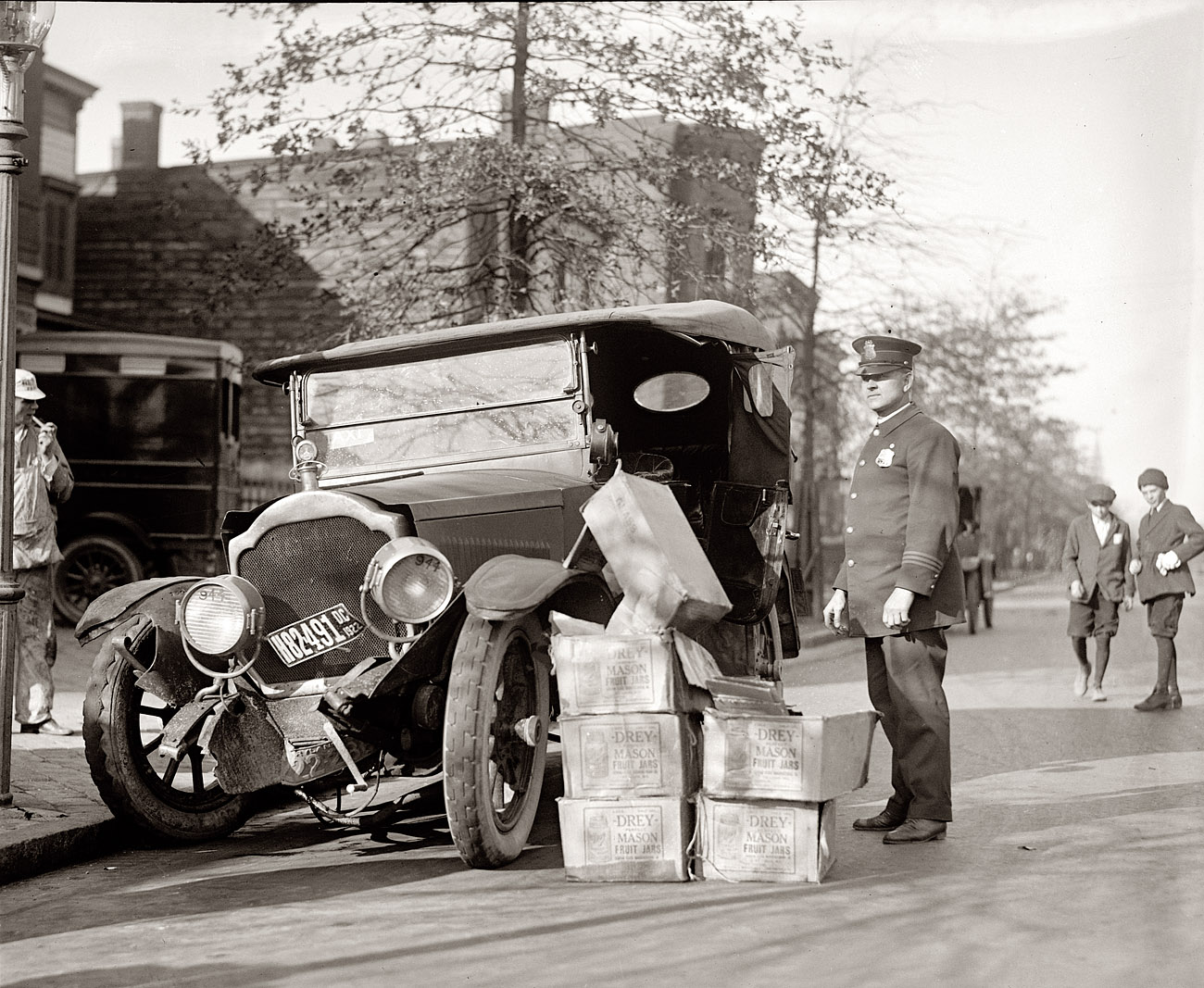 November 16, 1922. Cases of moonshine next to wreck of bootlegger's car in Washington, D.C. View full size. National Photo Company Collection.