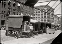 Washington, D.C., circa 1917. A Victrola talking machine on the delivery wagon at the Woodward &amp; Lothrop department store. Harris &amp; Ewing. View full size.
Open windows.Its interesting to me that we have lost our connection to the street in our cities with inoperable windows.  Back then you could open your window, get fresh air, and hear the sounds and smells of the street (for good or bad).
Seems like now our buildings have become blank facades with no life to them.  Not like back then anyways.
The buildings seem more alive to me back then.  That same buildings, today, would probably seem just a bit more sterile (albeit wonderful architecture!)
Bills of ladingWell into the 1960s and perhaps later, these Victrolas  and other audio products (radios, phonographs, tape recorders etc.) would be listed on the shippers' bills of lading as "talking machines."
Freight technology and registrationsSomething that always catches my eye on old photos like this is the fact that you can see horse-drawn vehicles sharing the streets amicably with the new-fangled automobile, though evidently the older method of transportation was giving way to the new technological marvel by this time; there's only one wagon in this photo, while I can count at least 9 automobiles. Maybe the fact that it was the only vehicle big enough to take that crate vertically was the reason why it hadn't been discontinued yet.
Also, have you noticed that the wagon does not seem to have a license plate? Makes me wonder if horse-drawn wagons were registered at all, like the automobiles.
Do Not StackOnce in a blue moon Victrola crates come up for auction, and all the ones I've seen have the curious cross brace covering the top panel.
I've always suspected that they were there to keep shippers from stacking the crates. Victrolas are very heavy, and I doubt stacked crates would survive shipment.
The Laurel and Hardy Transfer CompanyShades of "The Music Box" (1932) in which Stan and Ollie have trouble delivering a piano from their horse-drawn wagon, proudly emblazoned "The Laurel and Hardy Transfer Company, Foundered 1932, Tall Oaks from Tiny Acorns Grow"
Top Ship OnlyYes, I am sure that the 'peaked' cross-bracing at the top was to insure that no other crates were put on top at any point during shipment.  I've seen other furniture crates  built this way to circumvent the damaging force of something on top bouncing (horse drawn or hard rubber auto tires.)  The crate was designed to protect from side to side damage but could not support the weight of other freight on top without possible crushing, which would almost certainly damage the contents.  Gravity, while useful to most of us is quite a destructive force during shipping. 
(The Gallery, D.C., Harris + Ewing, Stores & Markets)