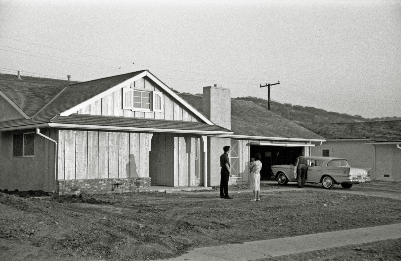 I thought I'd get on the 35mm black-and-white bandwagon with this one I shot on Kodak Plus-X in August 1963. A few weeks later my sister and her family moved into this, their new home in Diamond Bar, California. My brother (left) and I were down for a visit, so we all piled into their 1959 Rambler and headed out from their then-home base in South Gate to look the new place over. My sister is holding my niece, then 6 months old; I, seventeen years old, am behind the lens of my Kodak Retinette, then nine months old. Two years later, I stood on their front walk, turned around and took this shot. View full size.