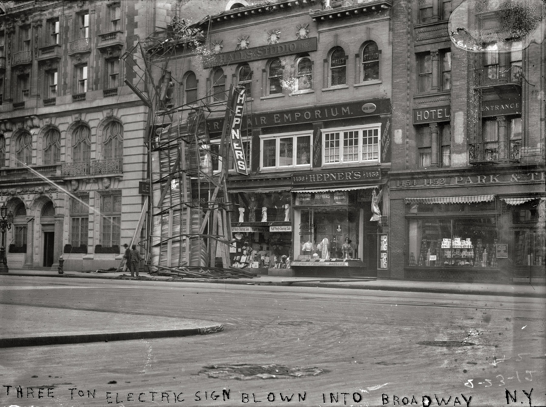 February 23, 1912. "Three-ton electric sign blown into Broadway." Our second look at the toppled sign in front of a railroad ticket office and Hepner's Hair Emporium. From the New York Times account the 100 mph gale: "An electric sign, 100 by 200 feet, on the roof of the Kohn Building, just south of the Hotel Knickerbocker, caught one of the worst puffs of the big wind and toppled over into Times Square. A policeman, who had just darted into the store on the ground floor to warn those within that the sign was coming down, barely escaped it as it fell. The sign, weighing nearly two tons, crashed over into the street, still clasped hinge-like to its moorings at the bent base, while the top, crumbling into the street, shattered to bits a large plateglass window in the Lehigh Valley Railroad's office on the ground floor." George Grantham Bain Collection. View full size.
