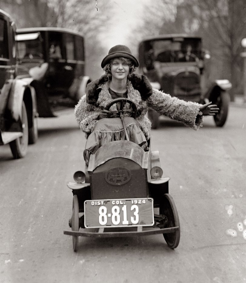 "The license plate is almost as large as her automobile, but Miss Mary Bay likes her car because it is easy to park. Miss Bay is shown braving the traffic of Washington." January 29, 1924. View full size. National Photo Co. Collection.
