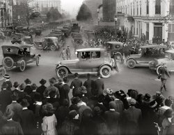 September 30, 1918. "Fourth Liberty Loan." Crowds gathered for a war-bond rally on Pennsylvania Avenue with the Capitol in the distance. View full size.
A smoggy dayThose old cars certainly did belch. Looks like LA!
Car-cophanyCough!
Nothing in the photo remains today Except the Capitol building: people, cars, buildings are all gone.
[Not so. The Willard Hotel is still very much there. - Dave]
Cough CoughRally for the American Lung Association to follow immediately.
My ChoiceI don't know what kind of vehicle it is but I'll take the sporty model in the center with the fine wire wheels and dual porthole rear windows. Anybody know what make that one is?
Waiting for Sousa?

Washington Post, Sep 30, 1918 


SOUSA TO HELP LOAN
Band of 300 Pieces Here Today for Parade and Concerts
Banks Will Remain Open Tonight and Tomorrow Night Until 9 O'Clock to Encourage Early Pledges - Part Payments of $5 and $10 Monthly on $50 and $100 Bonds Will Be Taken by Banks

Led by John Phillip Sousa, the famous Great Lakes Naval Band, which includes more than 300 pieces, will give a series of concerts today to help subscriptions to the fourth liberty loan.  The band is bigger and better this year than ever, and will be turned over to the liberty loan committee of the District for the entire day and evening.
The band will head a big parade through the streets this afternoon, will give two concerts during the day, and will provide a musical climax for the evening at a mass meeting to be held at 7:30 o'clock in Liberty Hut.
...
The Sousa Band will arrive early this morning on a special train, which is used throughout the country on behalf of the fourth liberty loan ... The band will proceed along B street west to Pennsylvania avenue, west along Pennsylvania avenue to Fourteenth street to H, west on H to Nineteenth street and Pennsylvania avenue, then east on Pennsylvania avenue to East Executive avenue, and south on Executive avenue to the south steps of the Treasury were a second big concert will be given at 4:30.
To offer every facility to the people for entering their subscriptions early all banks will remain open until 9 o'clock tonight and tomorrow.  Every bank will help persons of small means own a liberty bond by accepting $5 cash and $5 a month on a $40 bond and $10 cash and $10 a month on a $100 bond.
... 
Several buildings are still aroundIn addition to the Willard on the far left, the Evening Star Building, a sliver of which is visible just behind the Raleigh Hotel, still stands (at least its facade does). Farther down the street in the mist you can make out the twin spires of the Apex Building, also still standing. On the right side, turrets of the still-standing Old Post Office building appear just above the large tree.
Such a Great PhotoI am sure I am not alone as one who has forgone the endless drivel of the day's news to venture into the past with Shorpy, Dave, and the wonderful comments and observations of viewers which lead me to explore things I would have never questioned otherwise.
This photograph is one of endless wonderment as there is so much to see and ponder. A short list of what pops into my brain on viewing would include many unfit for comment and some that may be.  At first glance I thought it seemed a George M. Cohan production without enough flags.
How many people can I find in the crowd obviously aware of the  photographer? And of course the cars and trolleys. I am always taken by the lack of front wheel brakes on the autos of this period as I was in later years with the American designers painfully slow adoption of the disc brake and radial tire.
Today I explored brake history and found this:
http://www.motorera.com/history/hist07.htm
As Shorpy was voted one of the best 100 sites this year
it indicates that the appreciation for a quality undertaking has not been lost despite all evidence to the contrary. Thanks Shorpy.
Ike?I could not help but be struck by the resemblance of the Army officer at the right side of the photo to that of Dwight D. Eisenhower during this time period. I have spent the past couple of days looking up information and find he could well have been in Washington on that date. He commanded Camp Colt, Pa., but was reporting to Washington twice a week to the commander of the Tank Corps, who had his HQ there. I attach a photo of Eisenhower about three years prior to the Shorpy photo.
(The Gallery, Cars, Trucks, Buses, D.C., Harris + Ewing, WWI)
