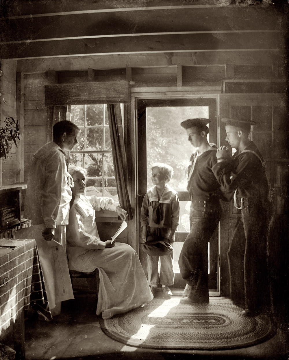 1913. "The Clarence White family in Maine. Mrs. Clarence White, seated by window in light, her husband and three sons in sailor outfits standing around her." 8x10 dry plate glass negative by Gertrude Käsebier. View full size.