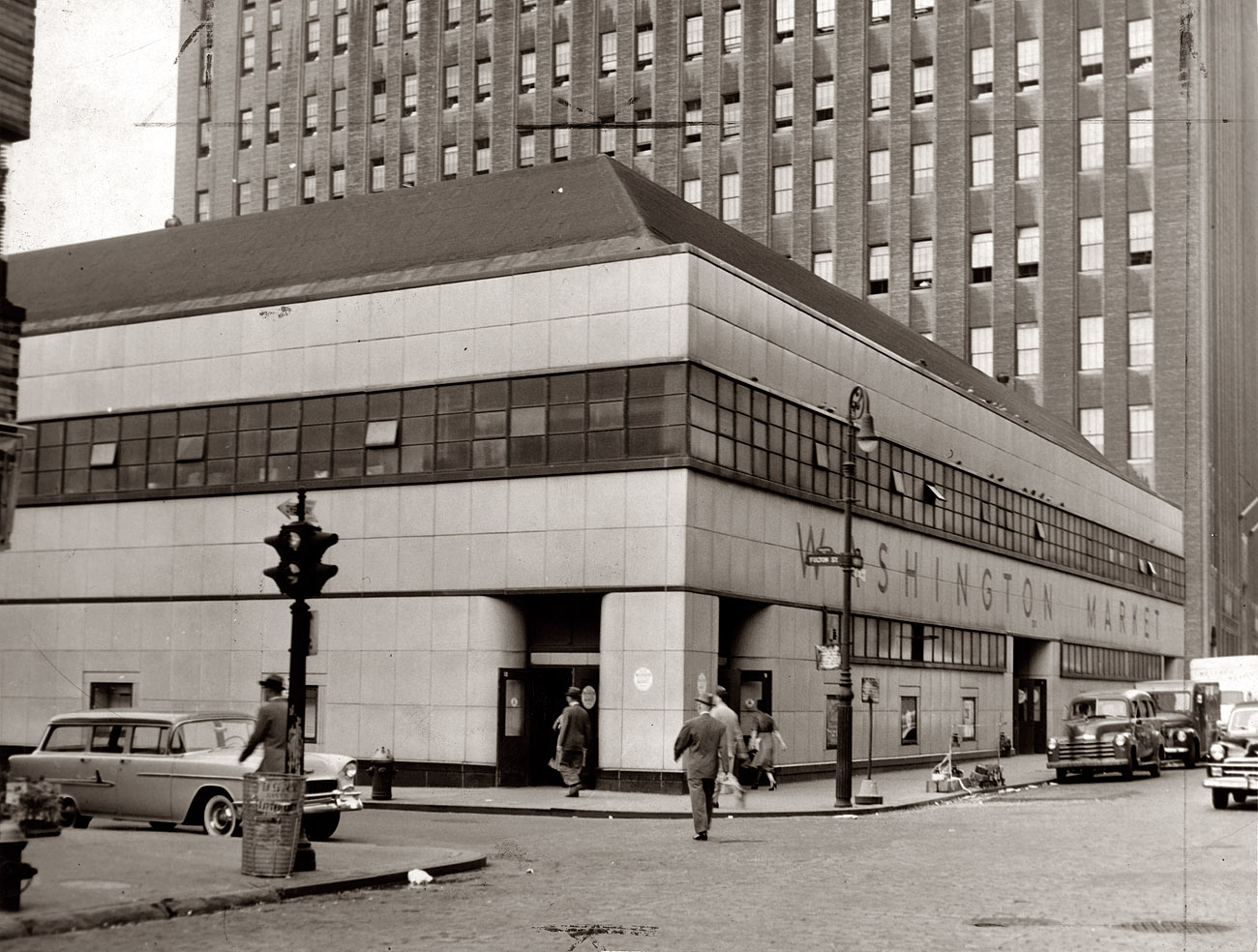 Part of Washington Market in 1956, looking north along Washington Street at Fulton Street in Lower Manhattan. The market, which began as an open-air bazaar in 1812, was renovated with the facade seen here in 1940 and razed in 1967 to make way for the World Trade Center. With more than 800 vendors, it was for many years the largest wholesale produce market in the United States. Photo by Fred Palumbo, New York World-Telegram & Sun. View full size.