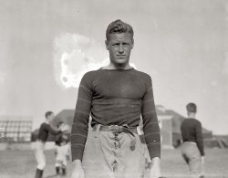 September 11, 1913. "Hobart Baker, Princeton football captain." Hobey Baker, better known as captain of the Princeton Tigers hockey team, was a World War I Army pilot who was killed when his plane crashed in France shortly after the signing of the Armistice. View full size. G.G. Bain Collection.
Three Sport ManHobey Baker not only played football and hockey, but in his freshman year was also on the baseball team. In these days of athletes specializing in single sports, it's hard to remember that there was a time when it wasn't at all uncommon for athletes to play multiple sports. The legendary Lionel Conacher played as a pro in five sports (Canadian Football, Hockey, minor league Baseball, Boxing and Lacrosse).
Holy Hobey.What a hunk...and a hero, to boot.
Fitzgerald&#039;s IdolF. Scott Fitzgerald and other Princeton underclassmen idolized Baker. Fitzgerald was supposed to have based one of his heroes in "This Side of Paradise" on him.
Hobey wowed not only Princeton but NYC as well. Society Swells in evening clothes  would watch his Tigers hockey games at Madison Square Garden where the marquee read "Hobey Baker vs. Yale". Games there sold out!
After college, Hobey eschewed going pro (after all, "gentlemen" didn't play for pay) but continued with amateur hockey. As an idealised and idealistic young Yank, he signed up as a pilot for the nascent Army Air Corp in WWI. 
When the war ended, the troops were readying equipment to be shipped back. Reportedly, he never asked his men to do anything he wouldn't do, so rather than allow his mechanics to test a repaired plane, he took it up only to crash and die in France. 
His tragically young death stunned so many of his generation. The NCAA Men's College Hockey annual trophy (think Heisman Trophy) is named the Hobey Baker
in his honor.
If they made a movie about Hobey, nobody would believe what an absolutely perfect gentlemen, scholar, athlete, and patriot the man was...
___________________________
This is all from memory, having read Michael McKinley's excellent "Putting A Roof On Winter".    
My goodness!Hobey sure was a looker wasn't he? Sounds like he was a class act too. Very cool. 
NamesakeBaker Rink at Princeton University is named after Hobey. You can see his skates and stick there. Skates look more like figure skates than today's hockey skates. A young Robert Redford would have been a good movie version of Hobey Baker.
(The Gallery, G.G. Bain, Sports, WWI)