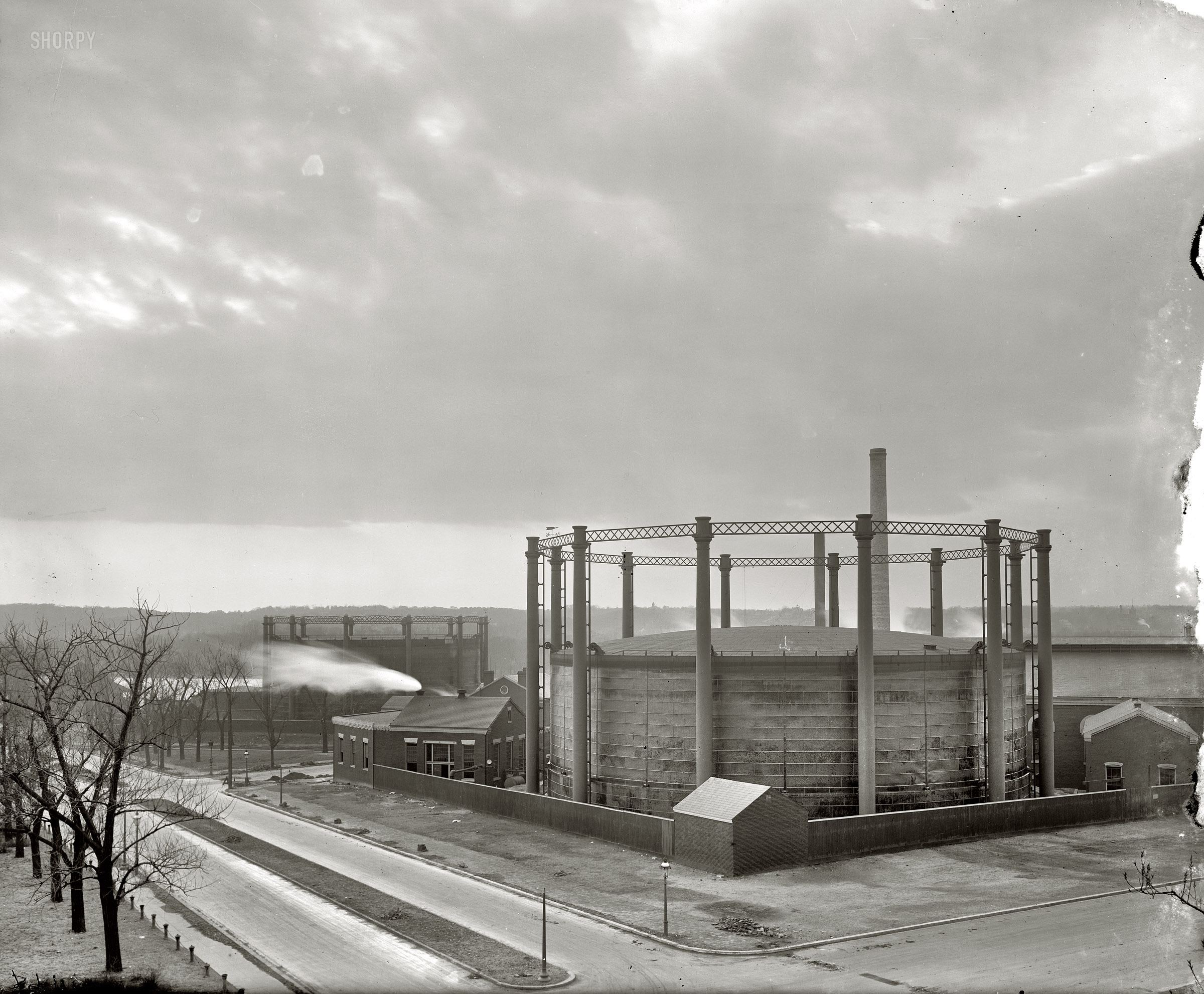 Washington, D.C., circa 1917. "Washington Gas Light holders at  26th and G streets N.W." These relics of the gaslight era ("two of Washington's biggest stinkers") were scrapped around 1947. Just about every city of any size in the latter half of the 19th century had its "gashouse district" -- a rough neighborhood dominated by smelly holding tanks for the municipal gas plant, where coal was gasified to make "city gas" (generally either "coal gas" or "water gas," depending on the process) for illumination. Harris & Ewing Collection glass negative. View full size.