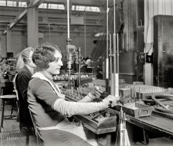 Philadelphia, Pennsylvania, circa 1928. "Assembling room, Atwater Kent radio factory." National Photo Company Collection glass negative. View full size.
Getting in tune The subject of this photo, an attractive young woman, looks to be assembling an adjustable (or tunable) capacitor. The metal plates of the movable half would move in and out from between the plates of the fixed half, thus changing the frequency that would be received.  She looks to be working on the movable part. 
I Like My Girls and Capacitors Variable Assembling the variable capacitors which were the heart of the tuning circuit of radio receivers and transmitters for decades.  One or more plates were mounted on a shaft which rotated the plates between a set of plates fixed on a base.  Your pocket 9 volt AM transistor radio had them, but they were a lot smaller.  With a few minor exceptions, micro chips have relegated variable capacitors to the electronic buggy whip bin.   
RxCarpal tunnel waiting to happen.
Amazing. You mean people used to work in factories, in this country, in the old days? And I thought everything was always made in third world countries. Wow.
[From the Shorpy Chamber of Commerce: Electronics manufacturing and assembly today employs many more people in the United States than it did in 1928. Below, workers at an Intel fabrication plant in Lehi, Utah. The biggest producer of manufactured goods on Planet Earth is not China or Japan but the good old U.S. of A.! - Dave]
Variable caps, or ??It looks like both the large disks and the smaller (spacer?) washers are circular. That won't work for a variable capacitor, as the rotating set of plates needs to present more or less extension in between a fixed set as the shaft turns. These could be Selenium rectifier stacks, for an AC-powered radio.
Variable NameNow more aptly named capacitors, up until at least the late '50s they were known as condensers. 
&quot;Amos &#039;n&#039; Andy&quot;went on the radio in 1928 and sold more radios than Uncle Miltie did TVs in 1950.  I'm sure Atwater-Kent, Philco, Zenith, and all the radio makers plus Pepsodent Toothpaste were most appreciative for that jolt in sales.
As Andy may have said "A'int dat sumpin!"
Variable CapacitorsThey'd be called variable condensers then.
I thought that's what they were but the plates seem to be complete circles, which won't work for a variable capacitor.
Capacitor vs CondenserIn this debate I look to that eminent Time Travel pioneer "Doc" Emmett Brown. (see 'Back to The Future', 'Back to The Future II, and 'Back to The Future III')  His revolutionary Flux Capacitor clearly shows that the term "capacitor" was accepted well before November 5, 1955.
Not a rectifierThis photo predates the invention of selenium rectifiers by 5 years. 
It was some time in the late 20s to early 30s that indirectly heated cathodes were invented to allow the filaments to be powered by AC electric. Otherwise, they had to use batteries which was inconvenient with the high current requirements of early triode vacuum tube filaments. 
Around the same time, more efficient pentode vacuum tubes were invented. They offered more gain which helped improve reception and reduced the number of amplification stages required in a receiver. 
re: Capacitor vs CondenserYou may be right.  In fact, we both may be right.  Or, less likely, I may be wrong.  In any case, happy clear-channel receivings to you.
Variable Cap for SurePhotographer posed capacitor so rotor plates could be seen. Atwater Kent produced Model 42 radio in 1928 which used three variable caps ganged together.  Model 42 used a tube in the power supply and not a selenium rectifier which were not produced until the early 1930s.  See picture of top view of Model 42.
It&#039;s a variable capacitor / condenserSelenium rectifiers weren't invented until 1933 so assuming the date on the photo is accurate it couldn't be a selenium rectifier.  Close inspection of the magazine holding the parts for assembly and the assembled parts in the back ground lead me to believe they are indeed "D" shaped and therefor a variable capacitor / condenser.
Re: &quot;Doc&quot; Emmet BrownNot only did he know it was a "capacitor", he knew how properly to pronounce "Gigawatt"!
Dave
(carefully de-splitting my infinitive)
BobsDid any woman NOT have a bobbed hairstyle in the '20s?
(The Gallery, Factories, Natl Photo, Philadelphia)