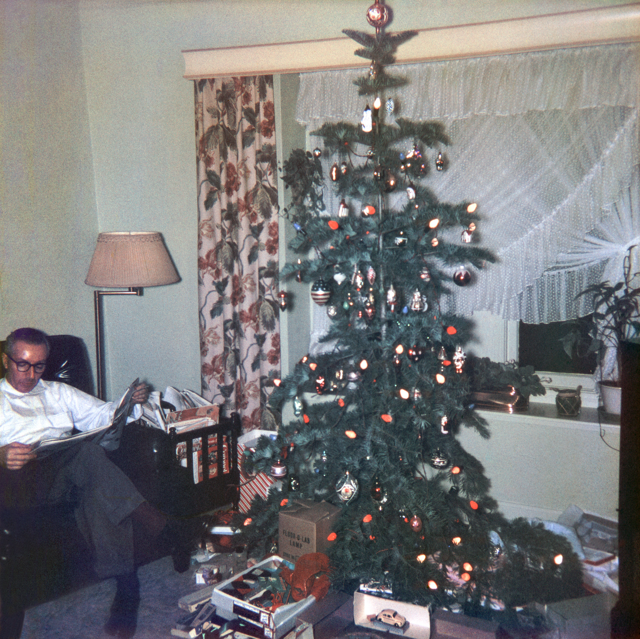 The gift-unwrapping frenzy past, and despite his being nearly crowded out of the frame, my father seems to be finding serenity by returning to normal daily routine, i.e. reading in his leather chair. Usually it would be the daily papers, but note the reserve stock of various publications overflowing the magazine rack. The tree and its environs can be seen pre-frenzy here in a post I made ten years ago. This shot was taken by my sister on 2-1/4-square transparency film. (Guess which of the discernible presents is obviously mine?) View full size.
