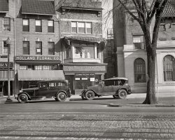 Washington, D.C., circa 1925. "Palace Laundry." 1811 Adams Mill Road N.W. National Photo Company Collection glass negative. View full size.
McCrory 5 &amp; 10?Could that be a McCrory 5 &amp; 10 on the left?
[Sanitary Grocery. - Dave]
Tree SignI've never seen a tree used as a signpost like this one -- ONE WAY DO NOT ENTER, wired about the trunk. The D.C. city traffic managers were obviously "green" long before their time.
Trendy neighborhoodThere's a BB&amp;T bank occupying the building to the right with the arched windows. That peculiar window that's halfway in the stone facade and half in the red brick is still there. There seems to be a cafe in the buildings to the left.
View Larger Map
ParkedCan someone identify the cars?
Slight Anomalies?Two things struck me about this photo.  First was the font used for the "Palace Laundry." In cursive, with all lowercase letters, it seems more like something from the 1940's or 1950's. Quite unusual, I think, for the time.
Second is the dark sedan on our left.  It looks just slightly later than 1925; with its curved, not squared, roof lines, I would have guessed it as a 1927 or 1928 model.
[It could be 1928. "Circa" means "around" or "approximately." Where are the car experts? - Dave]
CarsI think both cars are GM products. The one on the left looks like a GM product from 1927-1931, it's looks similar to a 1927 Buick and the car on the right looks like a 1919 Buick. I'm not 100% sure.
[Neither one is from GM. The car on the left is a circa 1928 Studebaker Dictator. The one on the right is a Hudson. - Dave]
Cars IIThanks for the info. I thought I'd give it a shot since noone else did. I'm not too familier with '10s and '20s cars. '40s and '50s cars I can name in an instant.
Adams-MorganThis is in an area now referred to as Adams-Morgan, party central for people in their 20s. I can't recall the name of the cafe on the left but it's big with the local kickball league.
Crazy CoincidenceI was going thru the DC 1935 Addresses and found that the relative I was researching was working at the Palace Laundry then. Thanks for posting the photo. 
Palace LaundryThe Palace Laundry and the Redskins have something in common -- both were owned by George Preston Marshall. In fact, Marshall's profitable laundry chain (which had more than 50 stores at its peak) enabled him to buy a pro football team, the Boston Redskins, which he moved to his hometown of Washington in 1937.
Incidentally, the Palace Laundry's slogan was "Long live linen."
The Missing Half Year &amp; The UnknownThe first car is a 1928 1/2 Studebaker.  The long hood length indicates this is actually a President 8 (the Dictator was on a much shorter wheelbase). 
The 1928 1/2 year models had a new narrower radiator design and a very short visor (military style) over the windshield.  The wheels are also unusual, but they are not unique to this year (they were definitely available in 1927 and both 1928 model years).
The 1929 closed Studebaker models had a curved "A" post at the windshield so it is easy to identify this as a 1928 1/2 year model.
The second car does not appear to be a Hudson.  On almost all Hudson's the Hudson triangle is visible on the hubcaps.  I cannot see any here (but the photo also does not show the hubcaps as clearly as I would like).  Also, the front of the grill should have a flat portion below the corporate logo for a Hudson.  Lastly, I cannot find any pictures of a Hudson with the large number of vertical louvers on the hood as seen here.
I would have guessed the second car as a Lincoln, but the grill also does not match.  I have not been able to determine the exact make of the second car.
(P.S. Based on the previously posted information should the title be updated to reflect the year 1928 or 1929 as well as the caption?)
Not a StudebakerThe first car is definitely NOT a Studebaker of any year or model. Nothing matches up including body shape, cowl lights radiator shell. Not sure what it is, but sure what it isn't! 
Disc wheelsThe large car with the disc wheels is a 1929 Nash. Their ad stressed the fact that their motor had seven main bearings making it exceptionally smooth.
(The Gallery, Cars, Trucks, Buses, D.C., Natl Photo, Stores & Markets)