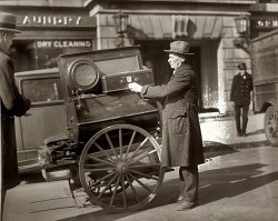 A street vendor and his radio-equipped cart circa 1928 in Washington, D.C. View full size. 4x5 glass negative from the National Photo Company Collection.
Old radioWe just sold that exact radio at an auction for $65.00.
I wonder how much it went for back then?
Atwater Kent RadioThis is an Atwater Kent model 55 or 60 Radio. These were AC powered sets, so where is the power coming from? These sets sold for about $100 without tubes. The speaker sold for about $34. They were quite popular and modern for their time (1929).
Radio IDI don't mean to contradict you Earl but if the date of the photo is 1925 then it can't be the Atwater Kent 55 or 60 since as far as I can tell neither was manufactured in 1925. The 1925 date makes it extremely likely that it was a battery operated radio from whatever company since Ted Rogers Sr. didn't invent the  first AC radio tube until 1925 and presumable they were pretty expensive in that first year of manufacture.
[The caption says circa 1925. Circa means approximately.  It's a guess. It could easily be a few years after that. - Dave]
Radio by the minute?So what was that guy vending? Radio by the minute?
If it wasn't a tube radio how did it drive that large speaker?
Hurdy Gurdy ManIt appears from the crank that this is a hurdy gurdy man who has updated his presentation with a battery powered radio. He was clearly a very with it gent. As Brent points out, batteries were the most common way and perhaps the only way to power a radio in 1925.  But where is the antenna?
On another subject, this negative has suffered some decay.  Can anyone identify the cause of the efflorescence?
[Looks like mold. - Dave]
AK RadioIt could be a "battery" model 67 with matching F7A speaker.
AK-55/60That radio looks very familiar, as I personally own an Atwarer Kent 60.  The 55 and 60 were identical, except the 60 has an additional tuning stage for fringe reception.  These models were introduced in 1929, and continued into 1930 and 31.  By the knobs it appears to be a later version, so I would guess the photo was taken around 1930.
One more note:  the standard 55 and 60 models were AC sets, but there were indeed variations available that used batteries.  This may have indeed been one of the variations.
Atwater KentIt looks like a battery cable going down to a box just in front of the wheel. If so, the set would probably be a model 67 with matching F7A speaker.
Pitchman In the depths of the Depression the daily 15 minute Amos and Andy show was afternoon break time. Barbers stopped in the middle of haircuts, bank tellers stopped vending money, and all at the time Amos and Andy came on the radio! For many years, from 1927 or so until 1943 Amos and Andy was the most popular show on the radio. 
This little street scene looks a great deal like an old time pitchman, perhaps with his cart loaded with some magic potion guaranteed to fend off everything from cancer to the social diseases, about to turn up the volume and gather a crowd, a "tip" in the pitchman's vernacular. 
 Thanks to the "vibrator supply, as soon as the 15 minute episode was over the spiel would start. 
That&#039;s a barrel pianoThe instrument on the cart is a barrel piano.  Not truly a hurdy-gurdy.  What most people call a hurdy-gurdy is more accurately a street organ or barrel organ or monkey organ (or, in Britain, a busker's organ).  Even these are not a true hurdy-gurdy. A hurdy-gurdy is actually a keyed wheel fiddle that is played by the operator, not a programmed barrel, roll, or book, and that dates back to medieval times. The simple fact that both the true hurdy-gurdy and barrel pianos and barrel organs are cranked has led to the blurring of the distinction between these various instruments.
(The Gallery, D.C., Natl Photo)